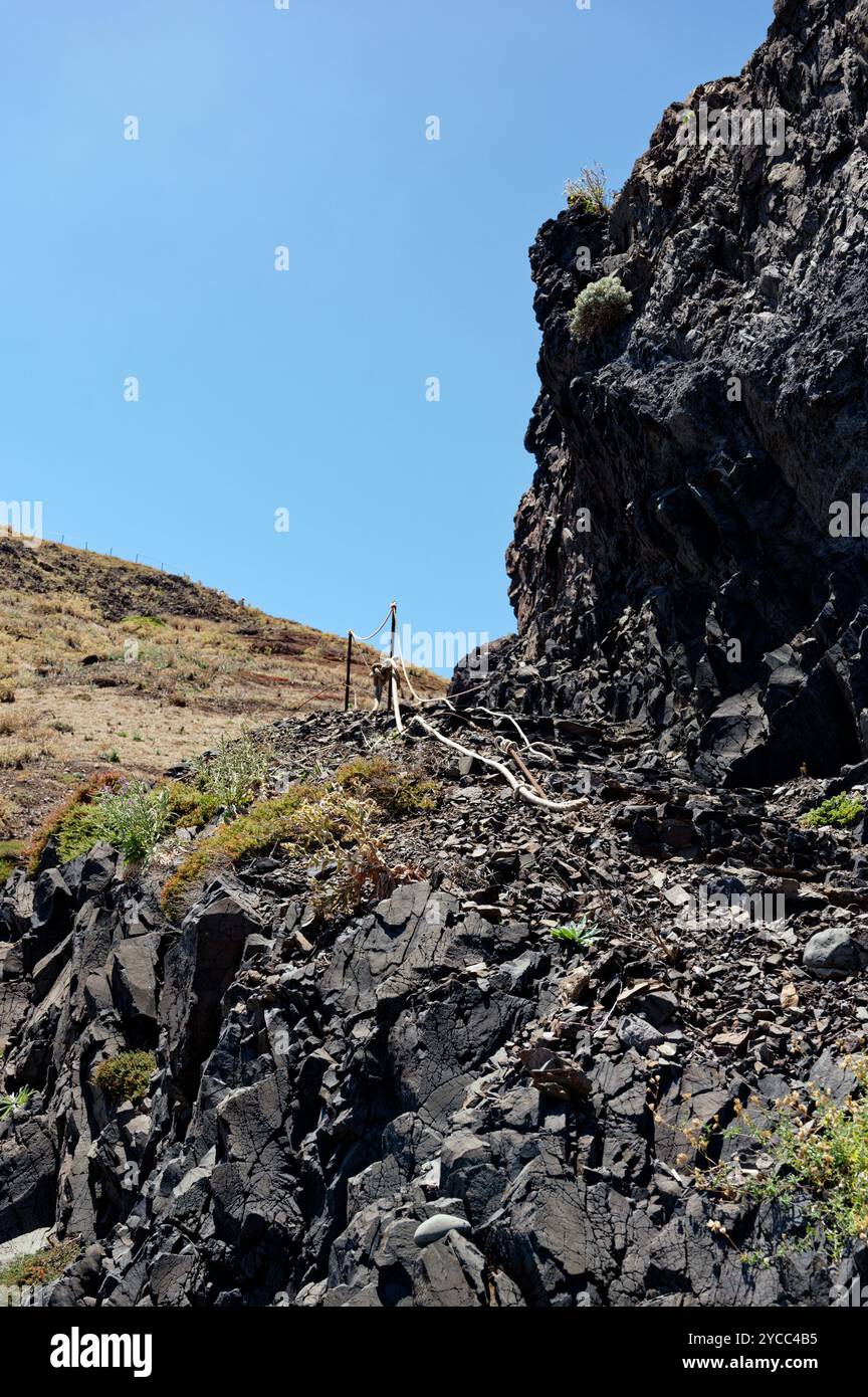 Ein felsiger Pfad schlängelt sich durch die zerklüfteten Klippen von Vereda da Ponta de São Lourenco, unter der hellen Mittagssonne Stockfoto