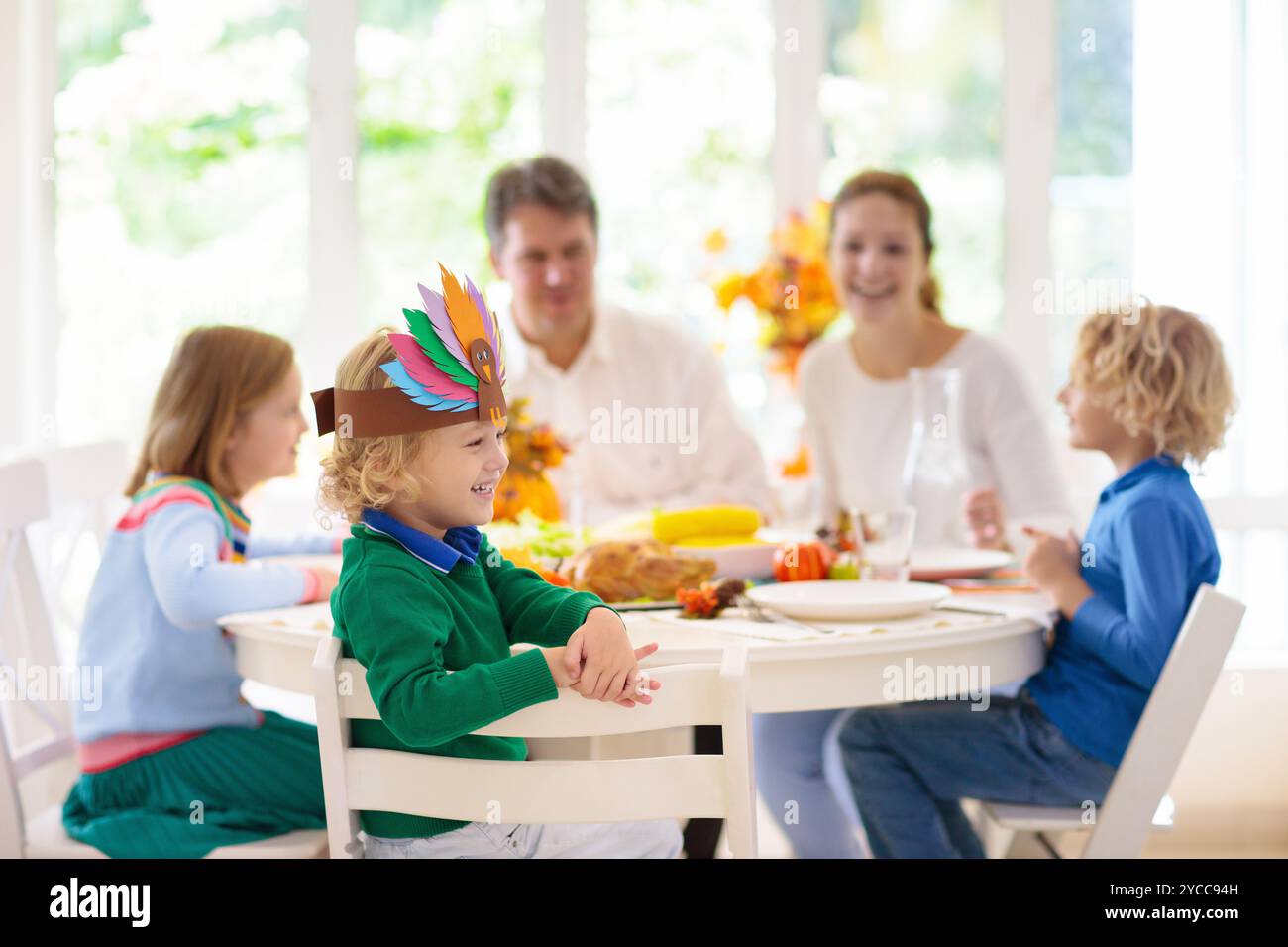 Familie mit Kindern, die Thanksgiving Abendessen essen. Geröstete truthahn- und Kürbiskuchen auf Esstisch mit Herbstdekoration. Festliche Mahlzeit für Eltern und Kinder. Stockfoto