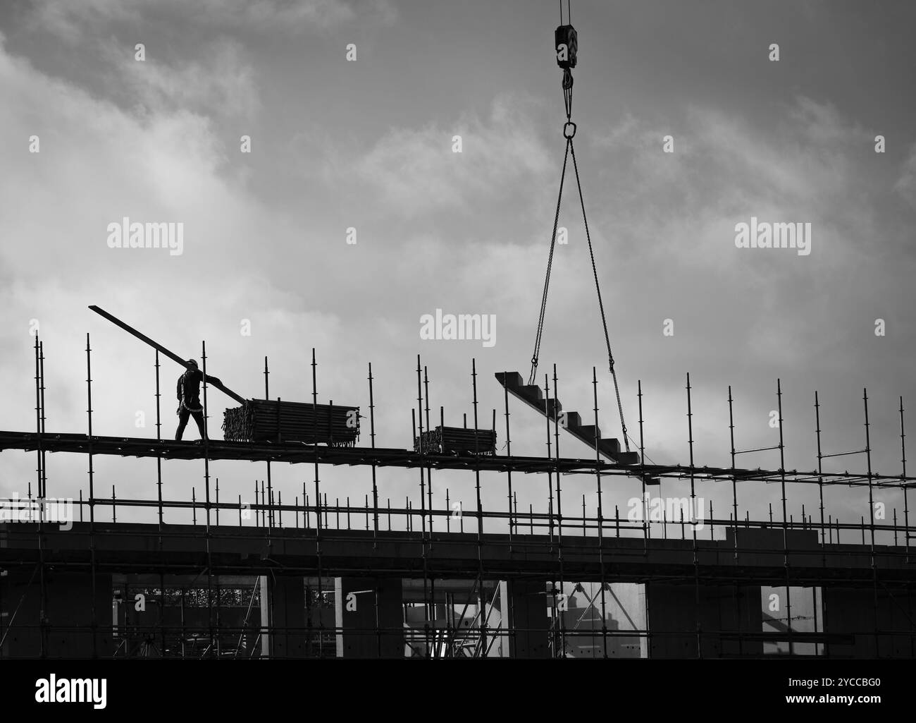 Szene von der Baustelle eines modernen Hochhauses mit Bauarbeiter auf Gerüsten in Silhouette Stockfoto