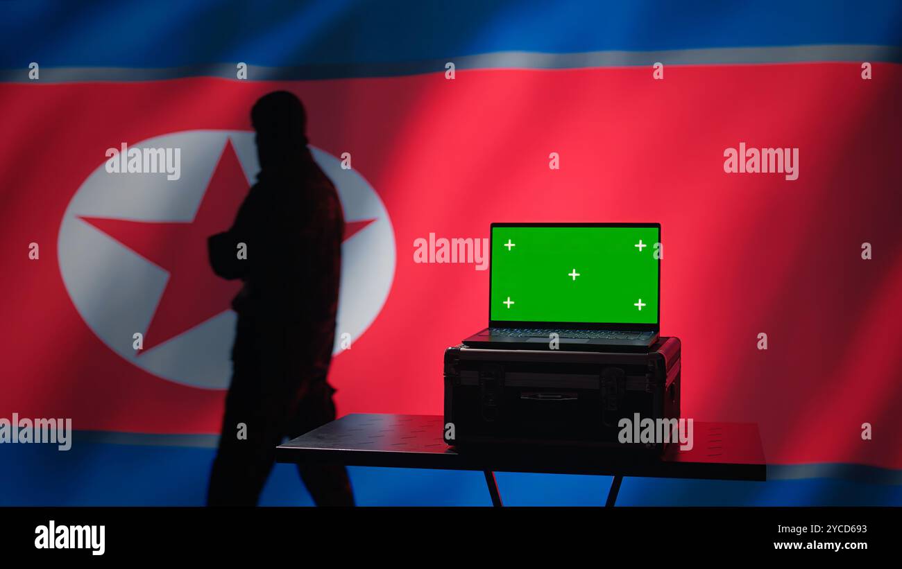 Der Geheimpolizistenagent Nordkoreas nutzt Massenpropaganda-Werkzeuge auf einem Green Screen-Laptop, um das Bewusstsein der Bevölkerung zu beeinflussen. Das Pjöngjang-Regime begeht PsyOP-Sabotage mit einem Modellgerät, Kamera B Stockfoto