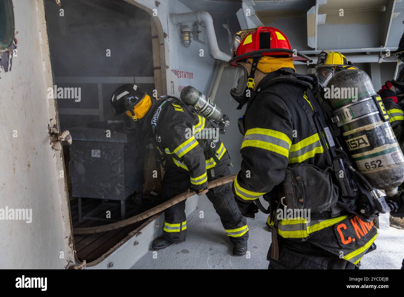 GEMEINSAME BASIS LANGLEY-EUSTIS, Va. – Feuerwehrleute aus mehreren Einheiten, die als ein Team arbeiten, bereiten sich auf den Eintritt in einen simulierten Feuerraum an Bord der SS Cape Avinof (AK-5013) während der letzten Veranstaltung des 32. Jährlichen Feuerwehrsymposiums in Fort Eustis, Virginia, 10. Mai 2024 vor. An dieser jährlichen Veranstaltung nahmen mehr als 100 Feuerwehrleute aus der ganzen Welt Teil, mit mehr als 50 Stunden Unterricht und praktischer Schulung in der Meeresumwelt, Terminologie, Schiffen und Einrichtungen sowie der Einarbeitung von Schiffen. (Foto der U.S. Air Force von Zulema Sotelo) Stockfoto