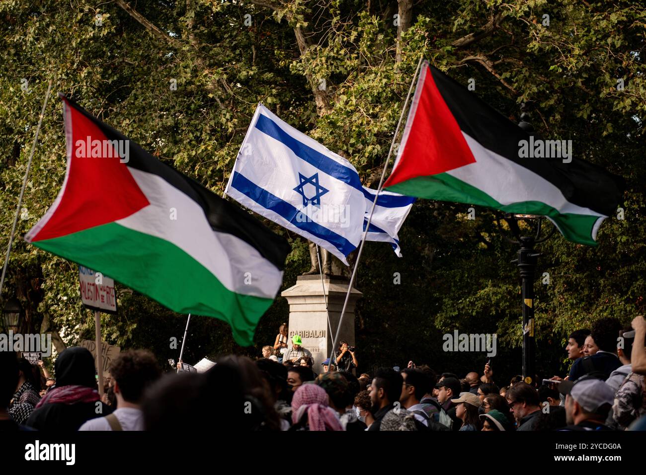 Manhattan, Usa. Oktober 2024. Pro-israelische und pro-palästinensische Demonstranten halten ihre Fahnen über einer Menge von Demonstranten während einer Massendemonstration im Washington Square Park. Hunderte pro-palästinensischer Demonstranten versammelten sich, um durch die Straßen von Manhattan zu marschieren, um gegen die militärischen Aktionen zu protestieren, die der Staat Israel derzeit in der Region durchführt, von denen Palästinenser sowohl im Gazastreifen als auch im Westjordanland sowie im Libanon betroffen sind. Quelle: SOPA Images Limited/Alamy Live News Stockfoto