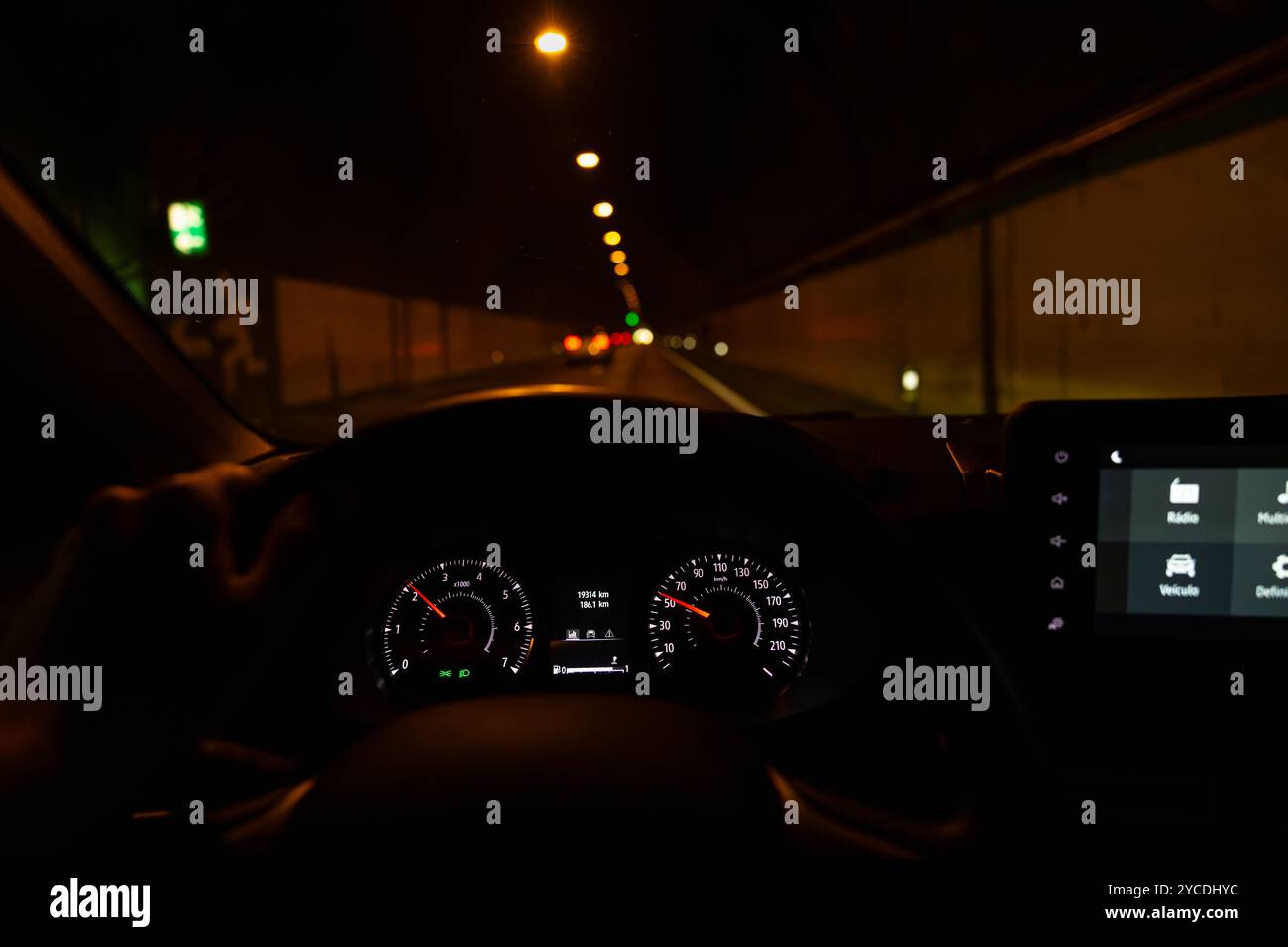 Ansicht des Fahrers zum Tachometer mit der Hand am Lenkrad. Verschwommene Tunnelstraße mit Verkehr vor uns. Insel Madeira, Portugal. Stockfoto