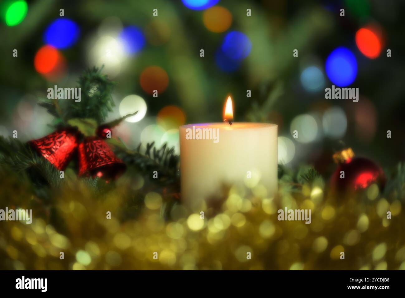 Weiße Weihnachtskerzen mit goldenem Lametta, roten Ornamenten und farbenfrohem Bokeh von Highlights und sanftem visuellem Ambiente Stockfoto