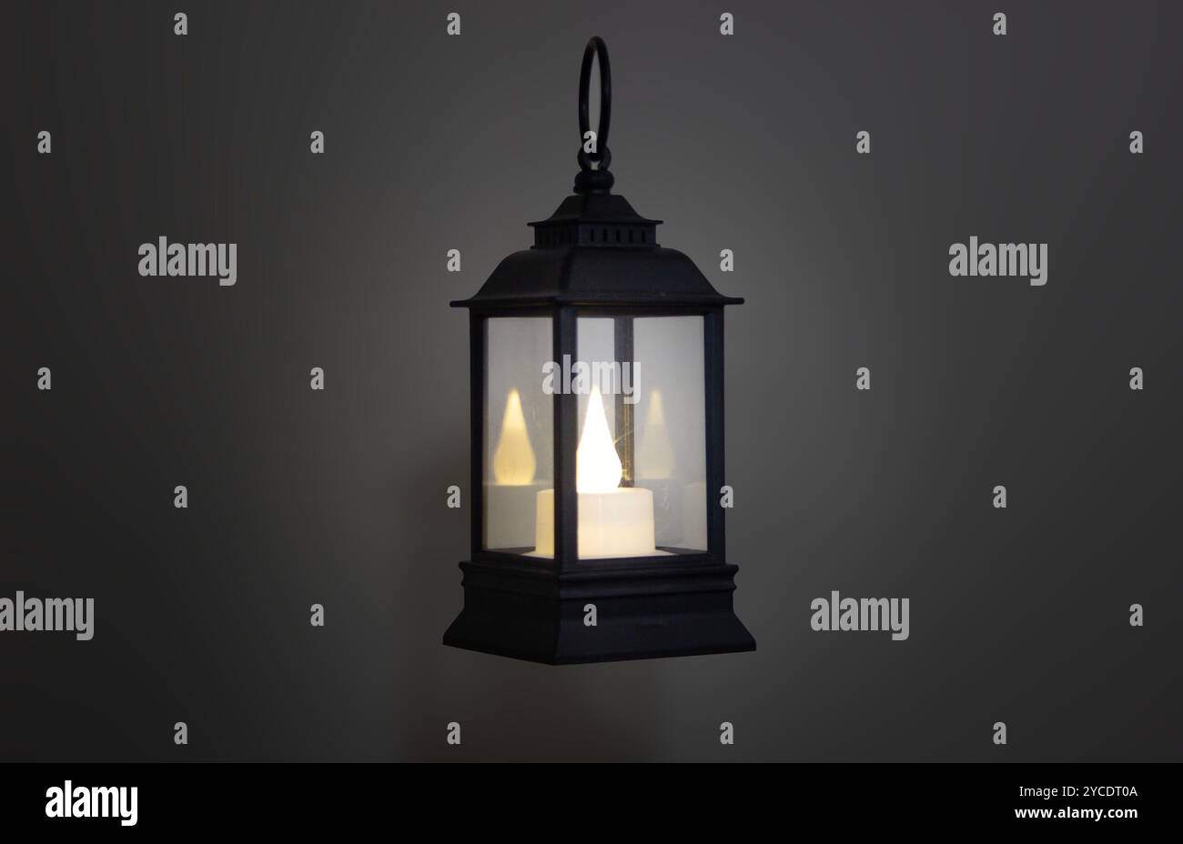 Eine Vintage-Laterne aus schwarzem Metall mit einem warmen Kerzenlicht leuchtet vor einem dunklen Hintergrund und schafft eine gemütliche Atmosphäre und rustikale Atmosphäre Stockfoto