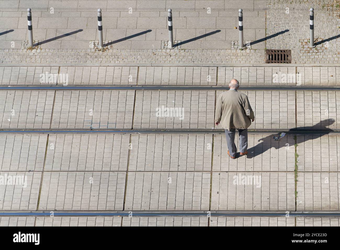 Alter Rentner im Stadtzentrum, der die Gleise einer Straßenbahn überquert, mit Textfeld auf der linken Seite Stockfoto