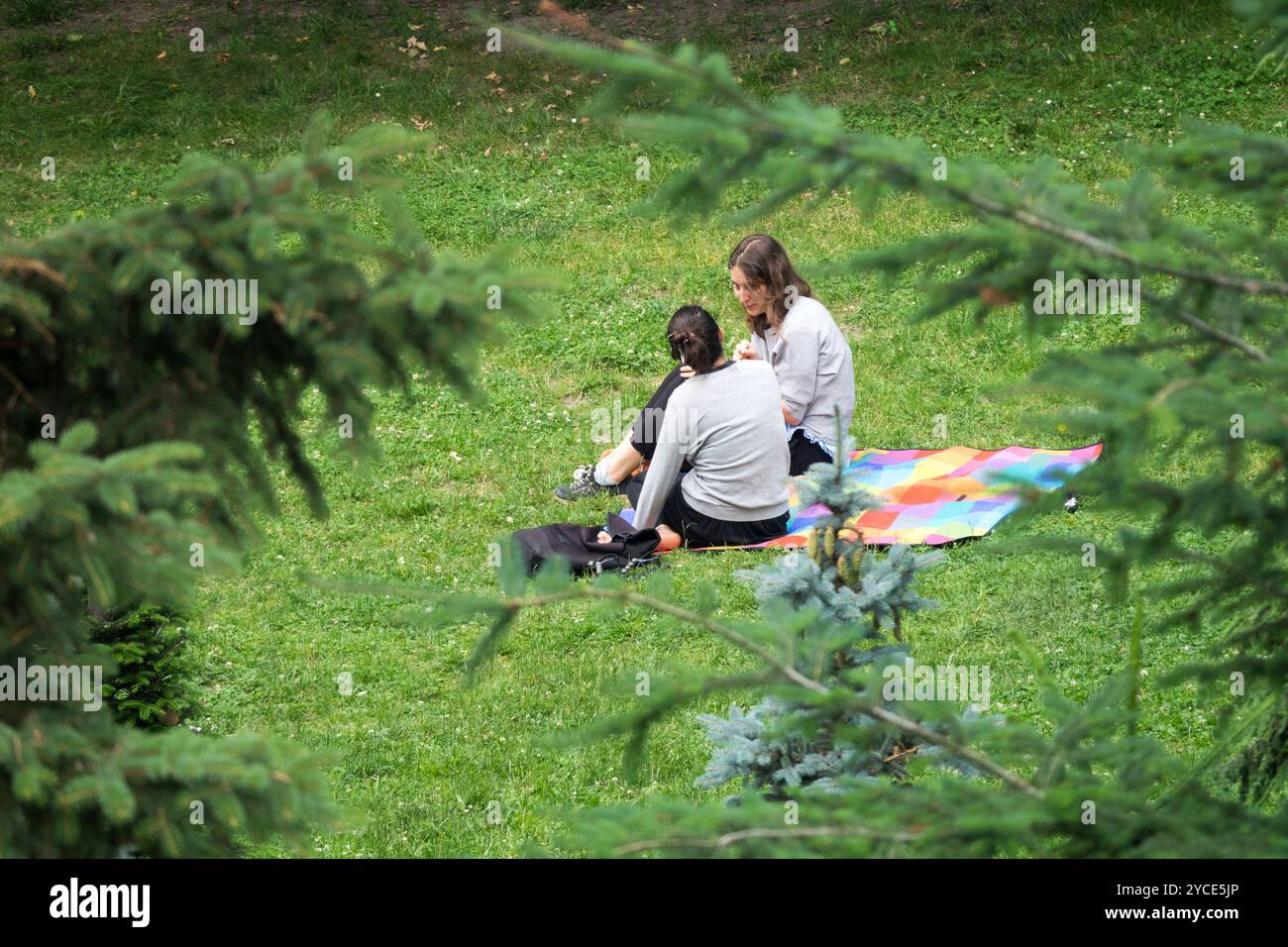 Zwei junge Frauen sitzen auf einer Decke im Park Stockfoto