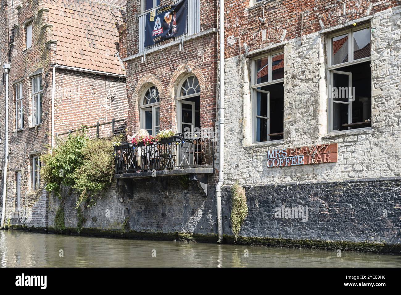 Gent, Belgien, 31. Juli 2016: Menschen sitzen auf einer Restaurantterrasse im Embankment Graslei im historischen Zentrum von Gent mit malerischem Altbau Stockfoto