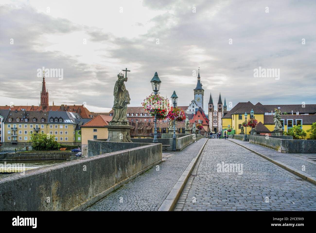 Fußgängerzone Alte Hauptbrücke und Panorama der mittelalterlichen Würzburger Stadt. Blumenabfälle und antike Statuen Stockfoto
