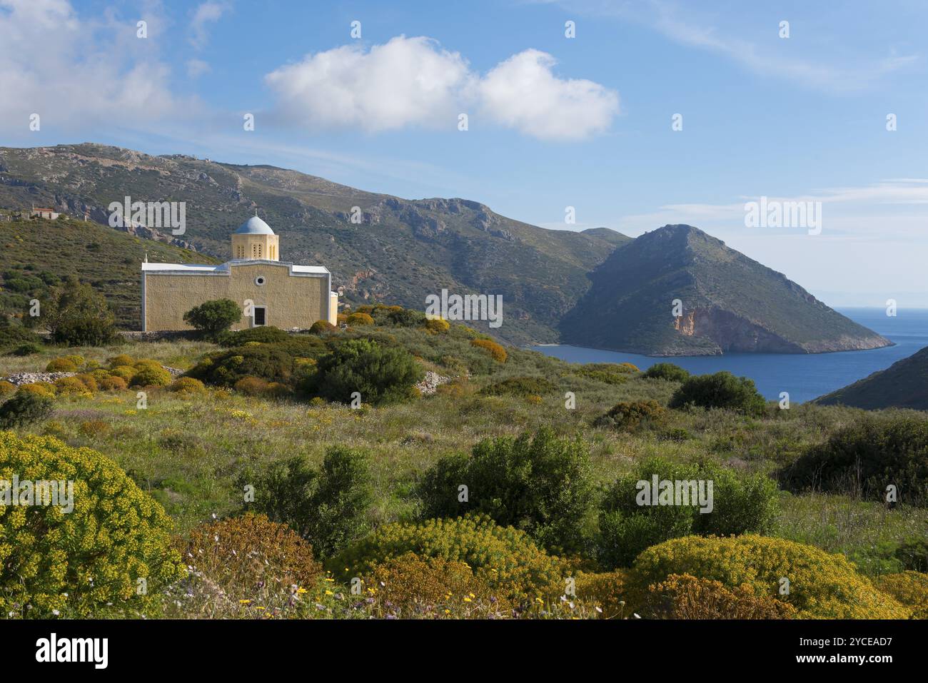 Kleine Kirche am Meer mit Bergkulisse unter blauem Himmel, umgeben von grüner Landschaft, Chiesa di Agia Triada, Kirche in der Nähe von Marmari, Anatoliki Ma Stockfoto