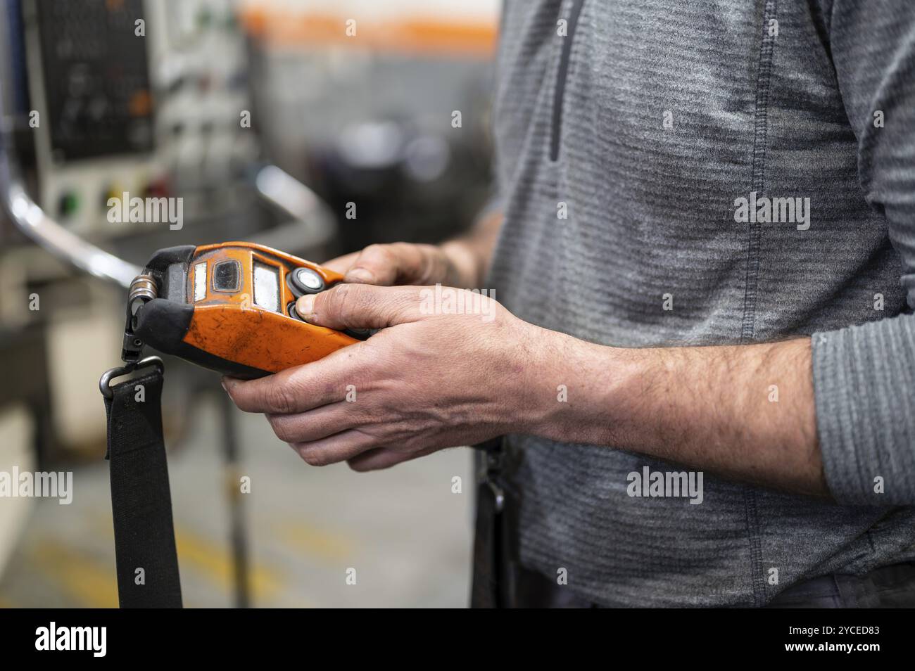 Fabrikarbeiter. Ein Techniker, der einen schweren Kran im Werk steuert, aus der Nähe eine Kransteuerung hält. Stockfoto