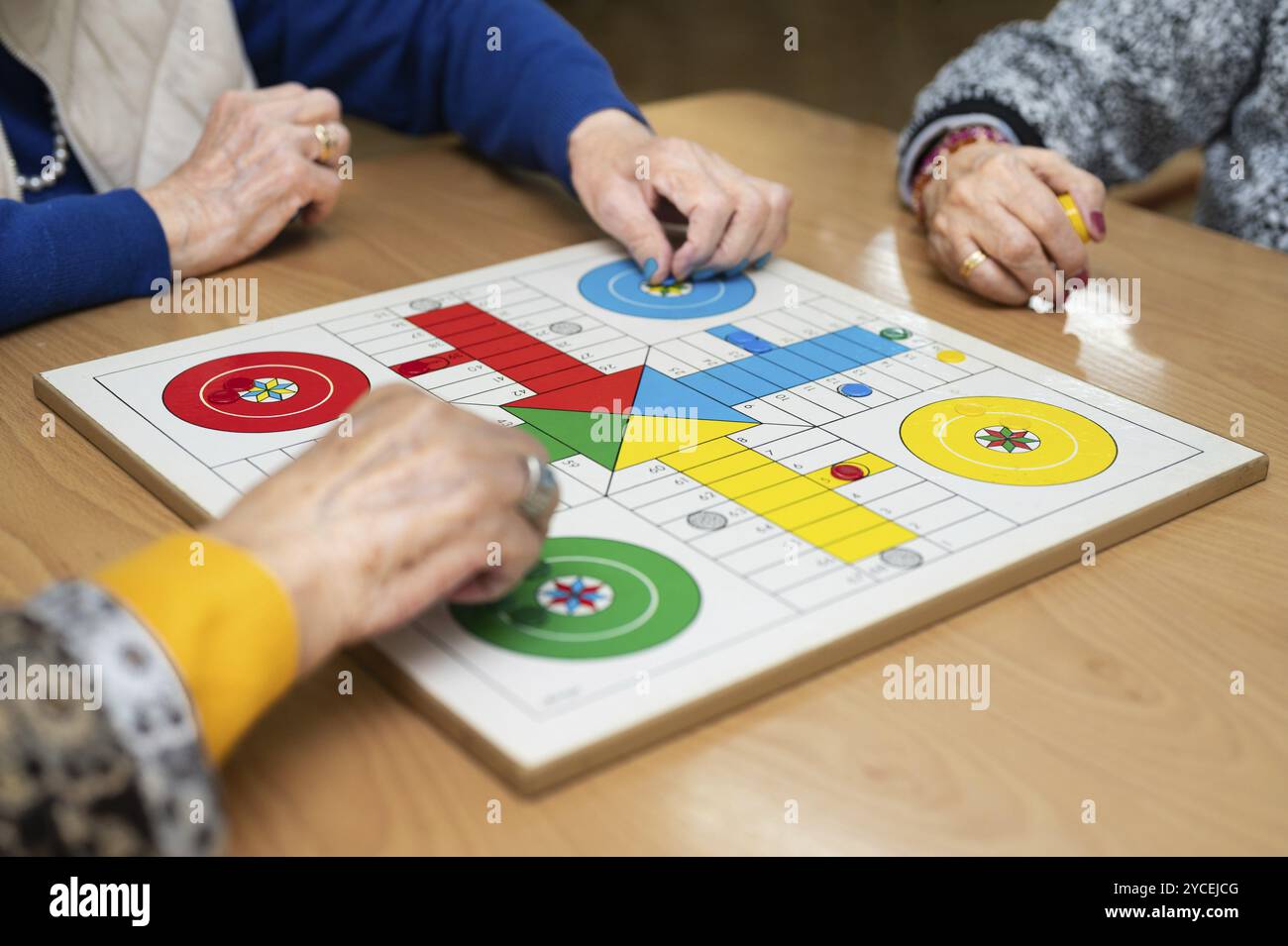 Gruppe von nicht erkennbaren Seniorinnen, die das klassische Spiel Ludo oder Parchis im Pflegeheim spielen. Stockfoto