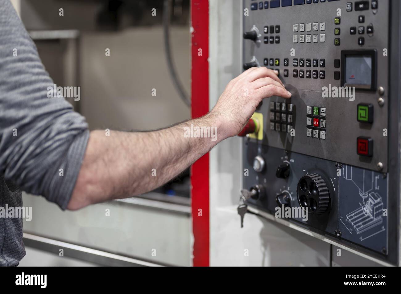 Arbeiter, der im Werk Knöpfe an der CNC-Maschinensteuertafel drückt. Grafik Stockfoto