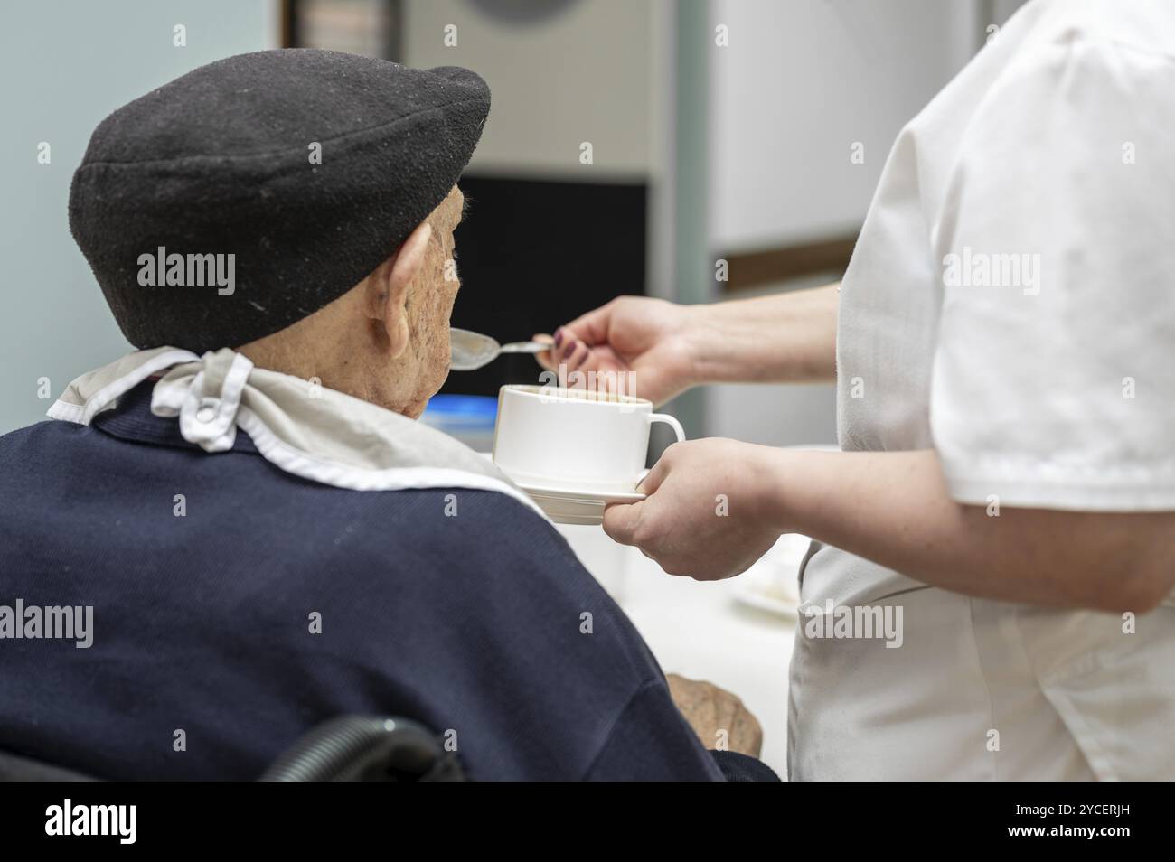 Seniorenmann, der im Pflegeheim von einer Pflegerin ernährt wird. Grafik Stockfoto