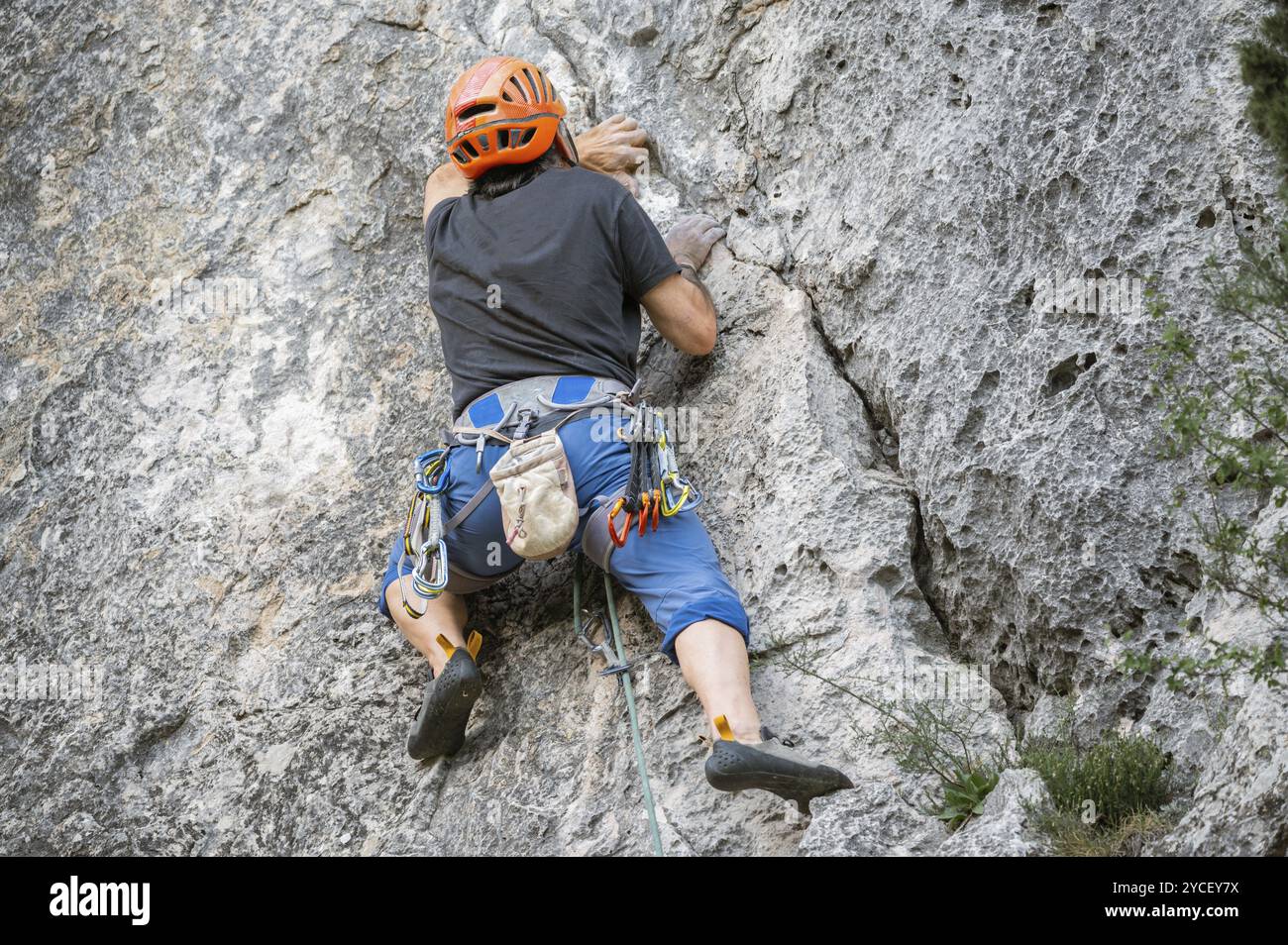 Nahaufnahme eines Kletterers mit Ausrüstung auf einem Gürtel, der eine Felswand klettert. Stockfoto