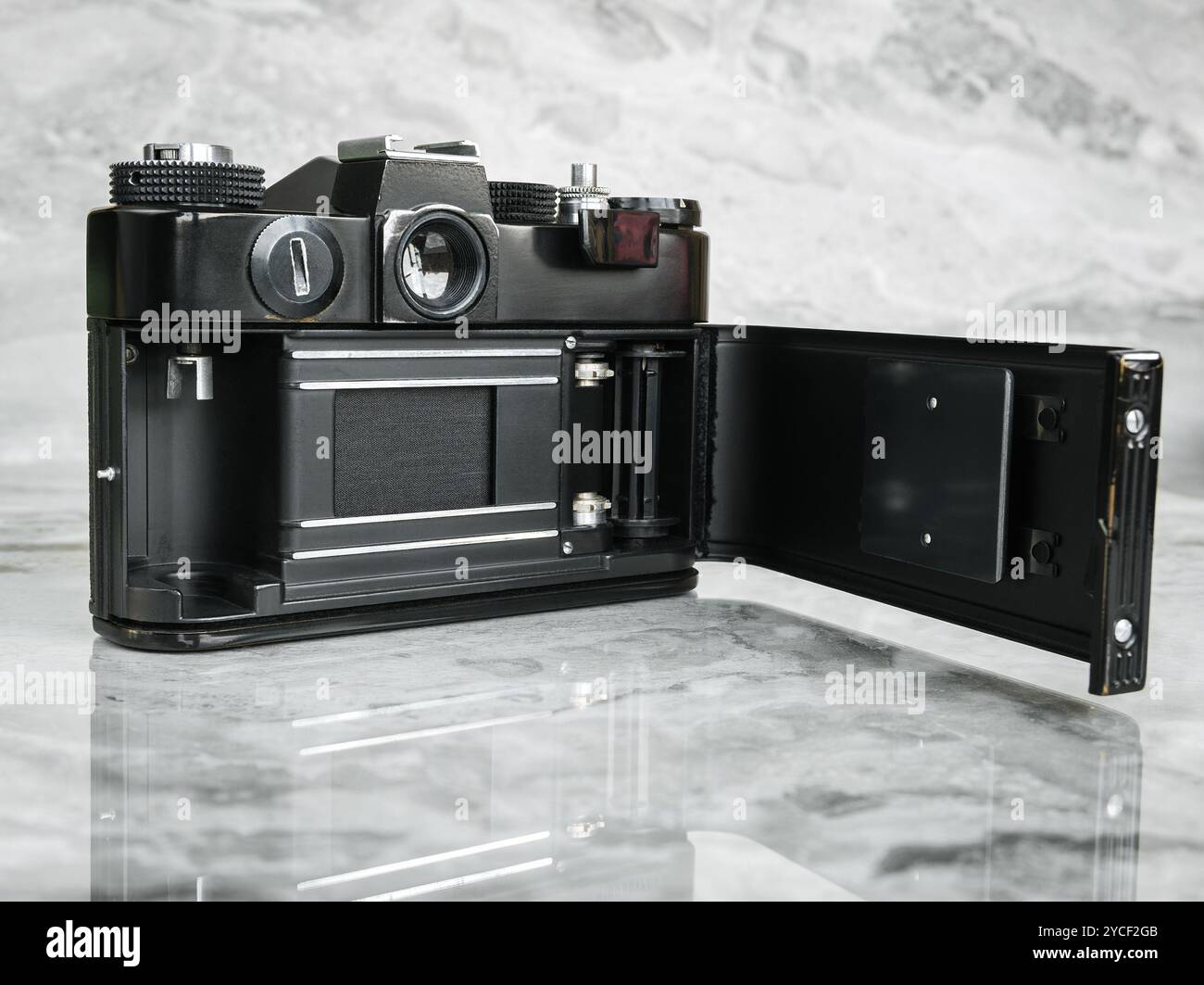Eine alte schwarze sowjetische Filmkamera mit einer offenen Rückabdeckung auf einer polierten Marmoroberfläche. Stockfoto
