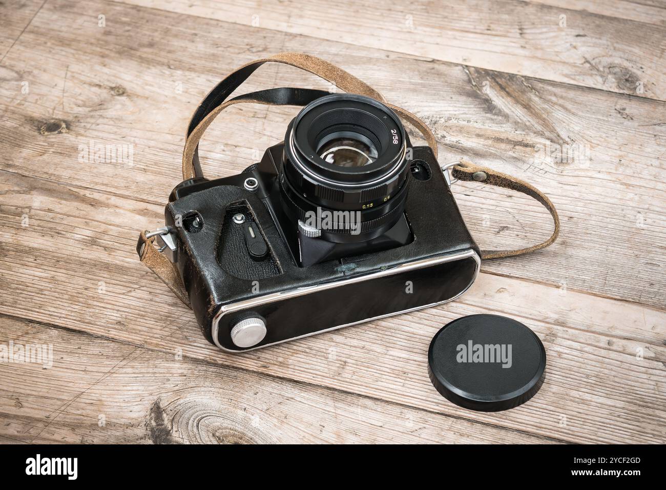 Schwarze sowjetische Filmkamera in einem Lederetui auf hölzerner unbemalter Oberfläche mit Knoten. Stockfoto