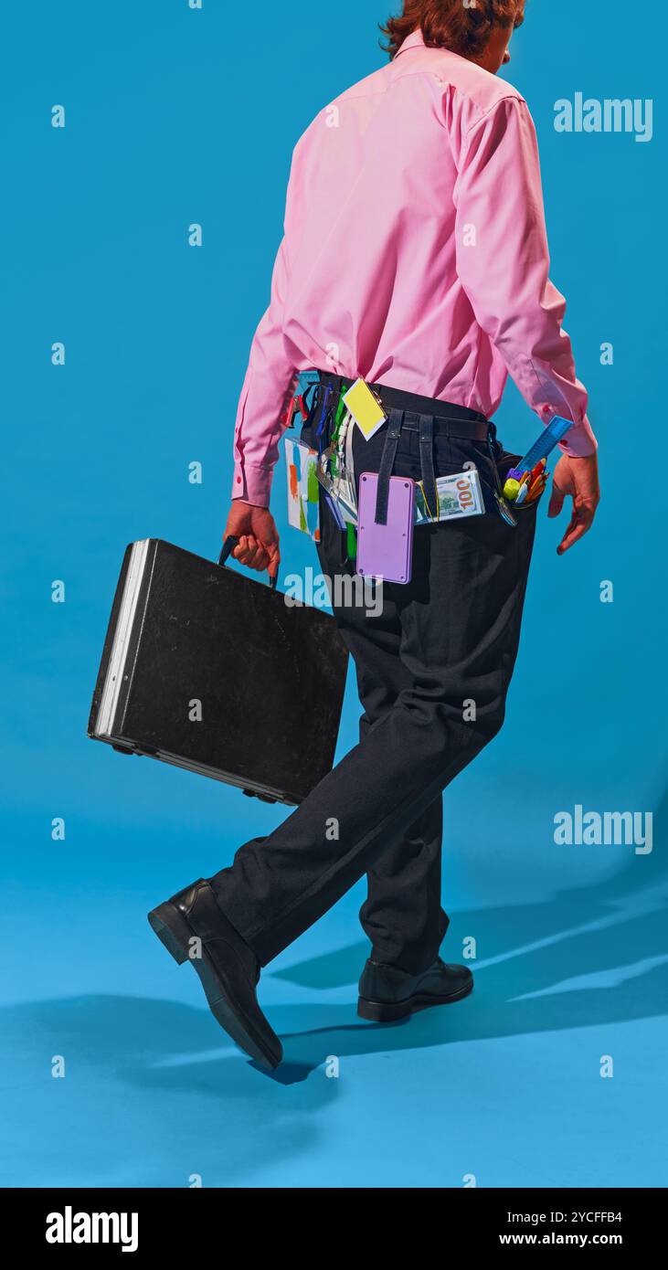 Mann, der mit Aktenkoffer weggeht, seinen Gürtel voll mit Werkzeugen, Stiften, Haftnotizen und Bargeld vor leuchtend blauem Hintergrund. Stockfoto