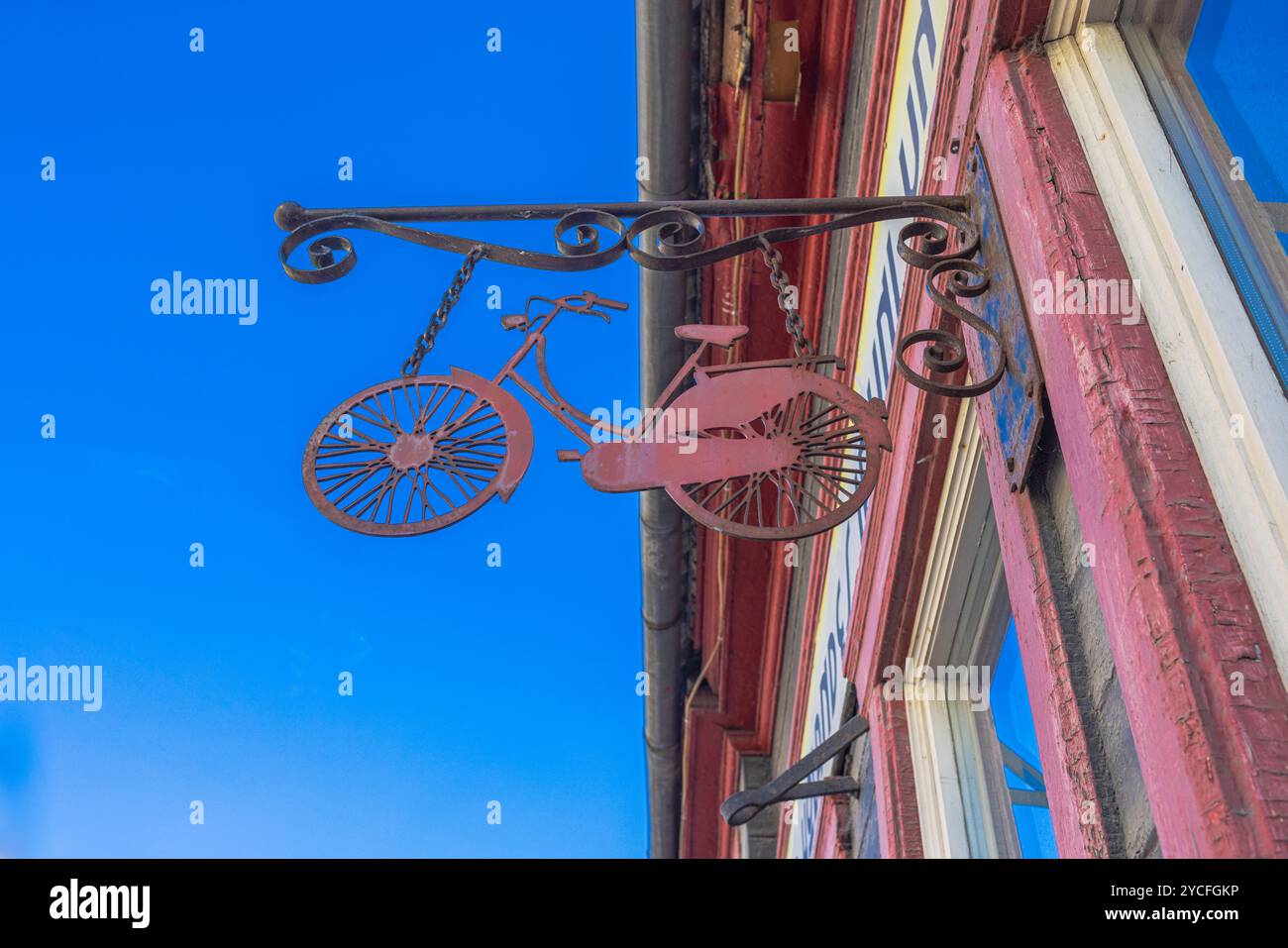 Ein dekoriertes Fahrrad hängt an einem hohen Ladenschild Stockfoto