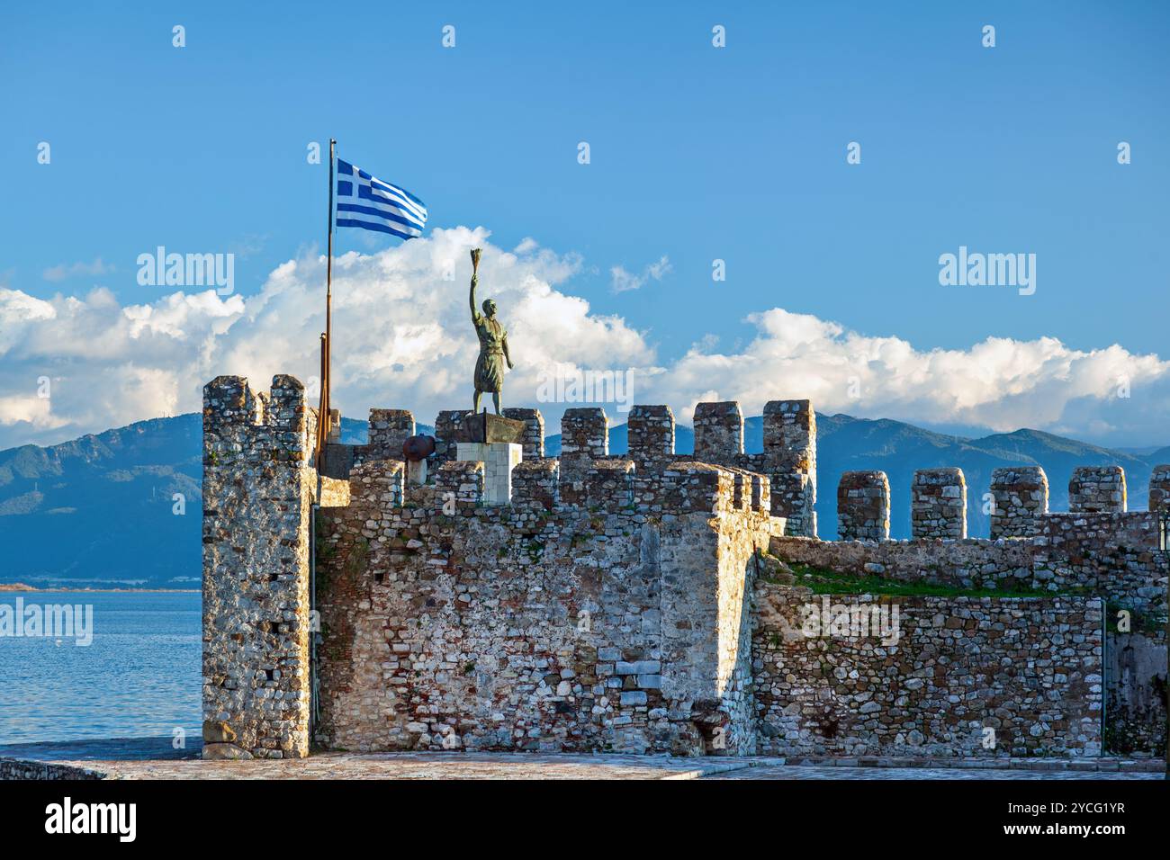 Hafenschloss Nafpaktos mit der Statue von Georgios Anemogiannis, einem Helden des griechischen Unabhängigkeitskrieges (1821), und einer griechischen Flagge, die winkt, in Griechenland. Stockfoto
