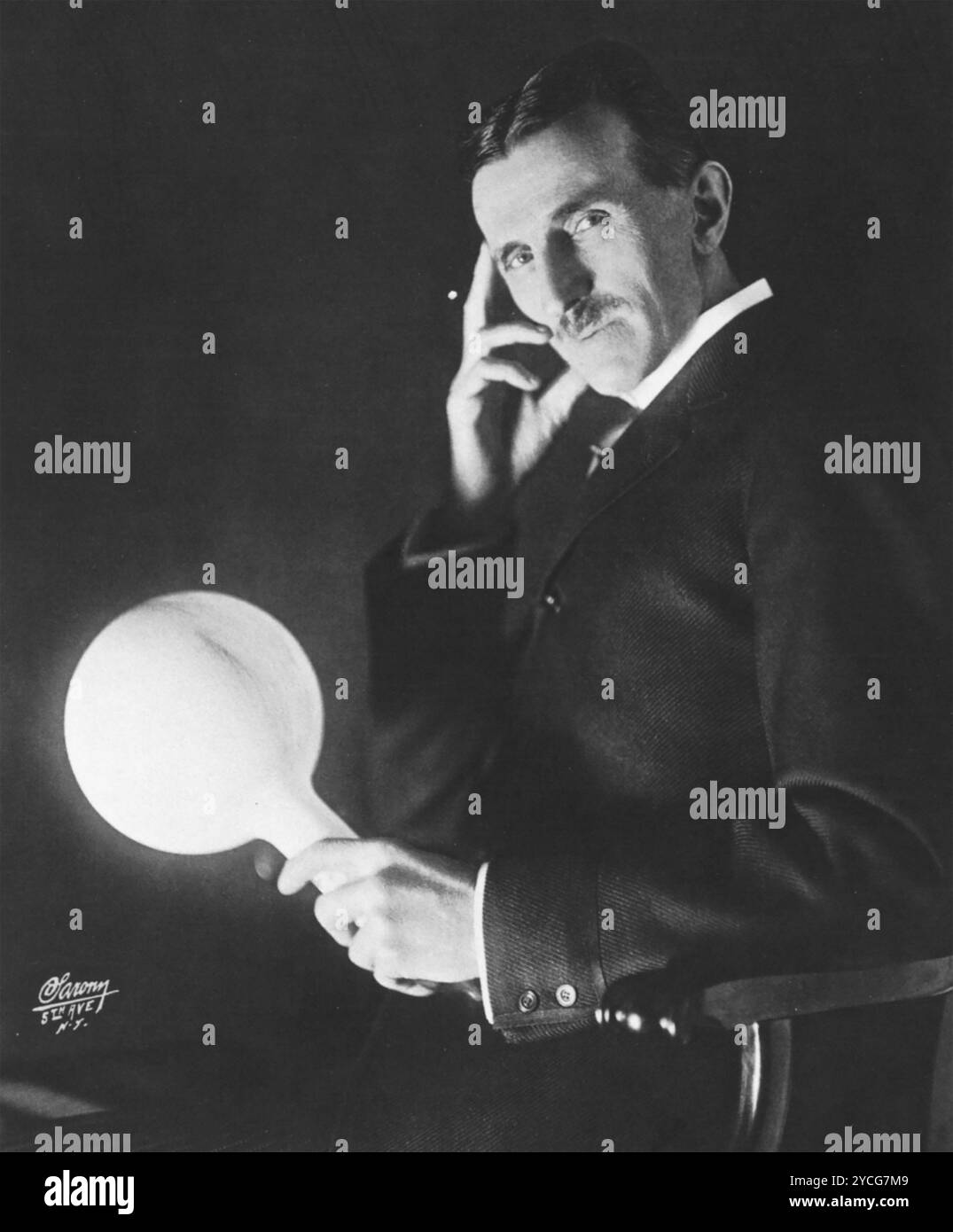 NIKOLA TESLA (1856–1943) Serbisch-amerikanischer Elektroingenieur auf einem Foto von Napoleon Sarony aus dem Jahr 1898. Tesla hält eine Lampe ein paar Meter vom Generator entfernt, während sie weiter leuchtet. Stockfoto