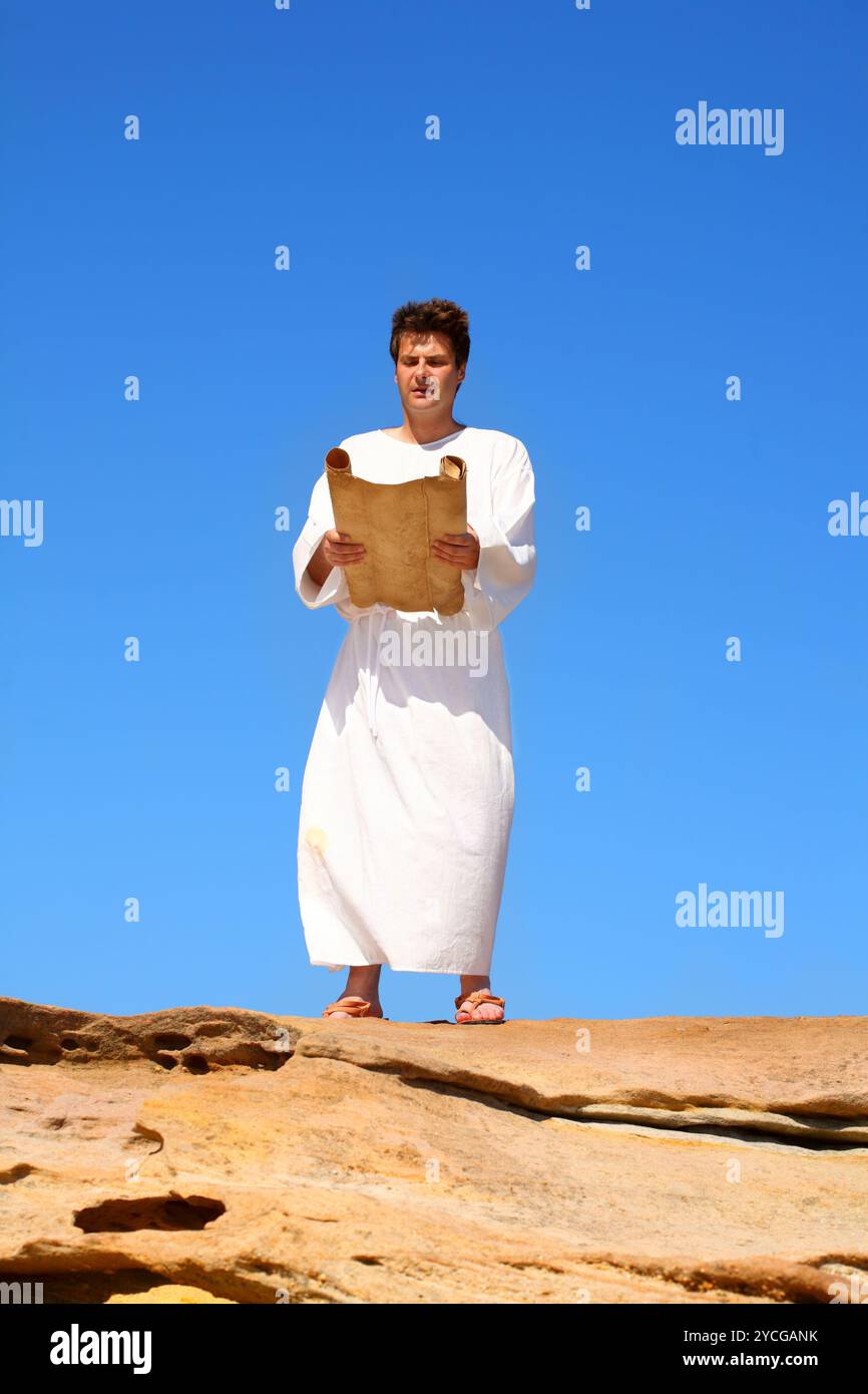 Ein Mann liest Schriftrolle in felsiger Wüstenlandschaft Stockfoto