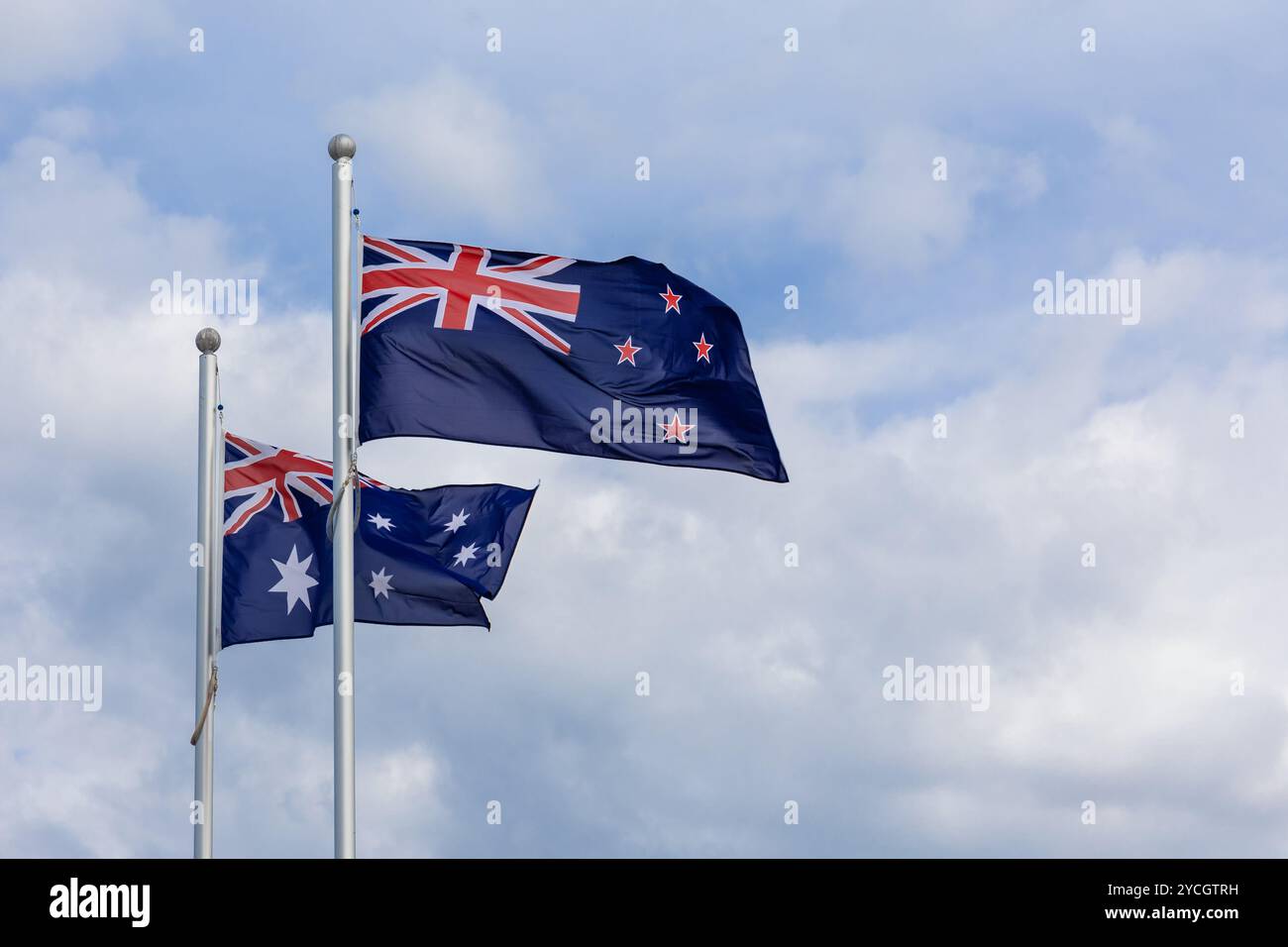 Nationalflaggen Neuseelands und Australiens fliegen nebeneinander vor blauem Himmel Stockfoto