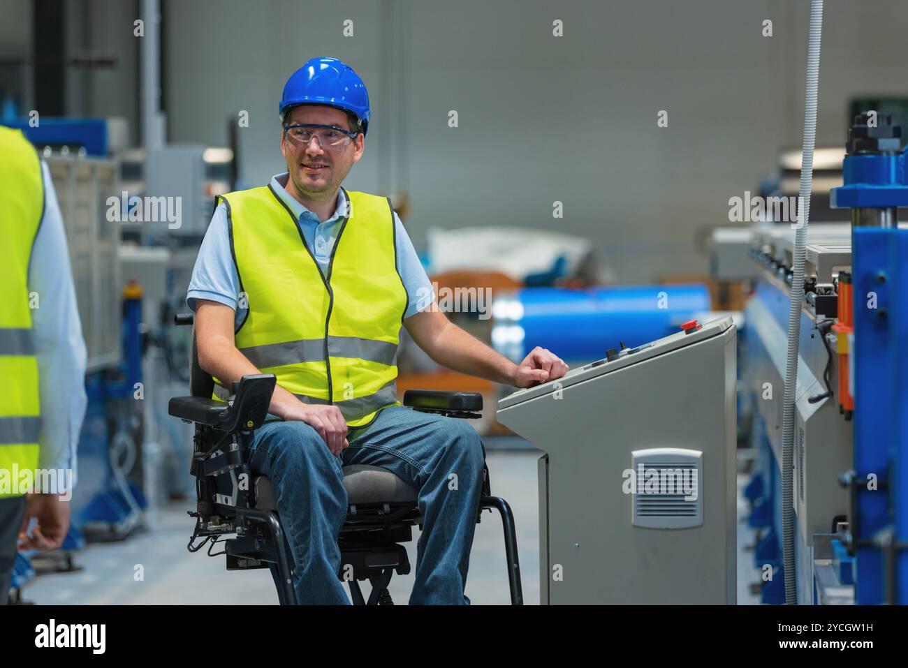 Fertigungsingenieur mit Behinderung in einer Fabrik mit gelber Weste und blauem Helm bei der Arbeit. Stockfoto
