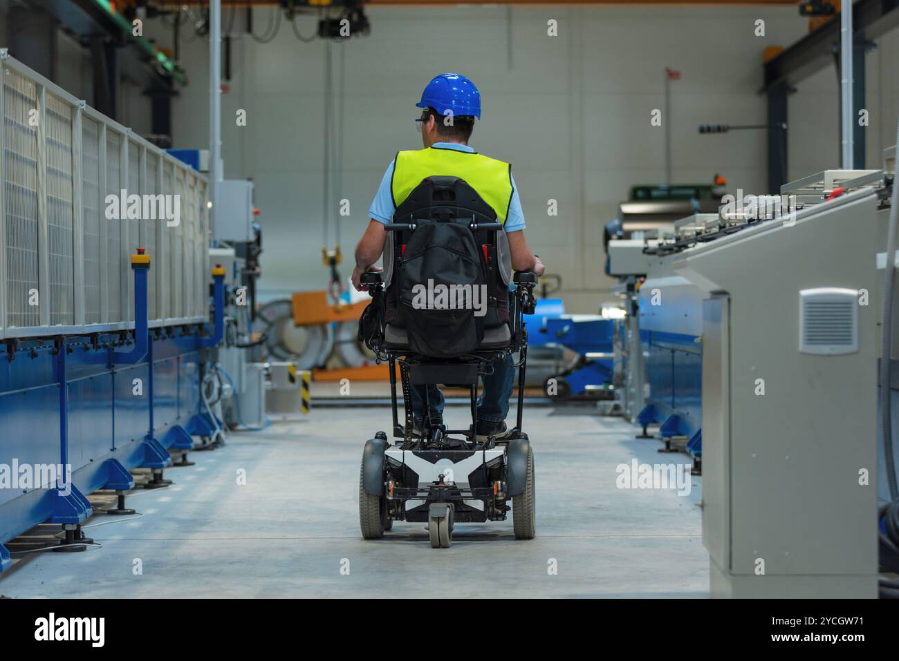 Fertigungsingenieur mit Behinderung in einer Fabrik mit gelber Weste und blauem Helm bei der Arbeit. Stockfoto