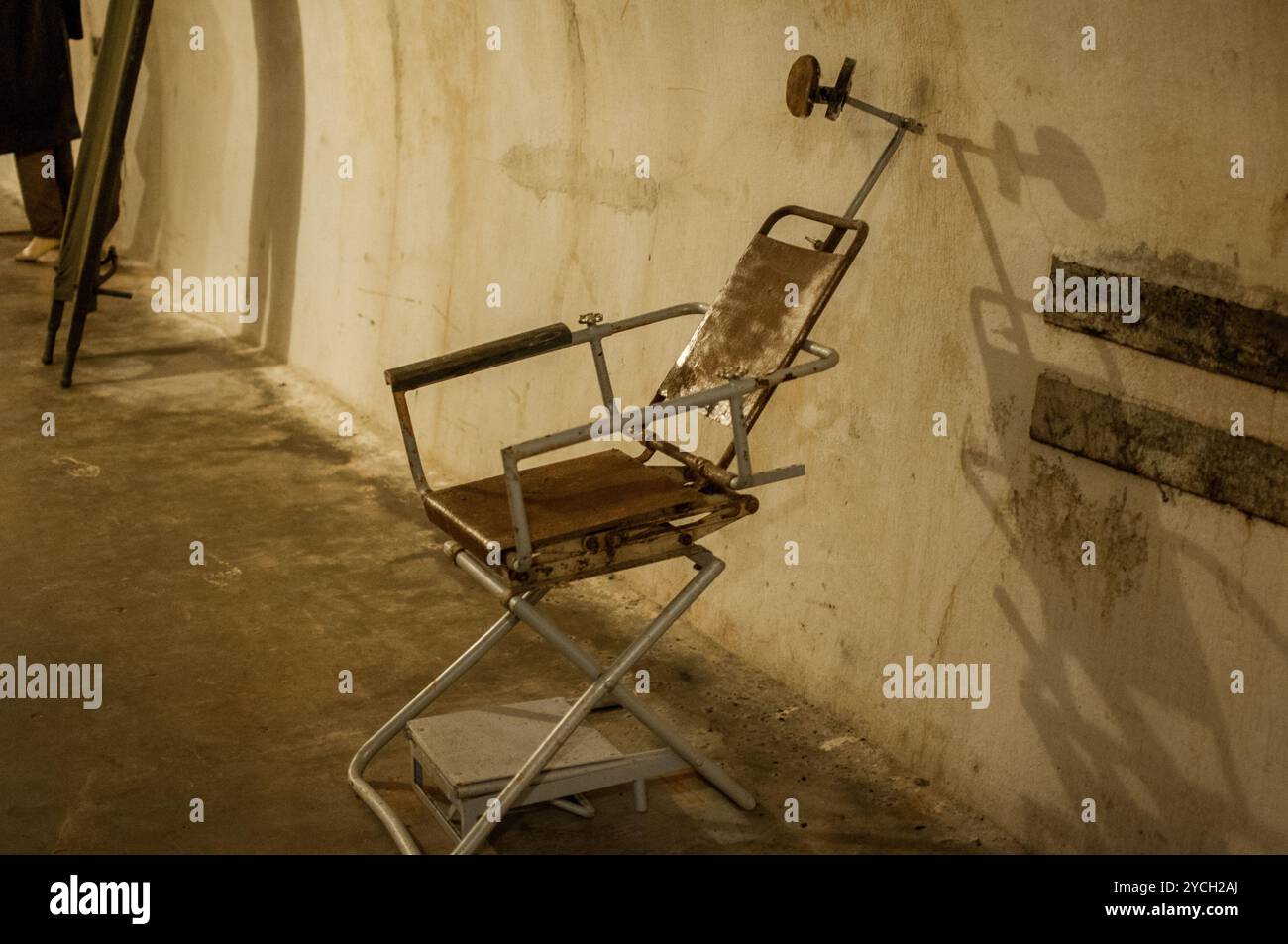 Vergessener Untersuchungsstuhl in einem schwach beleuchteten Raum mit Vintage-Ästhetik. Stockfoto