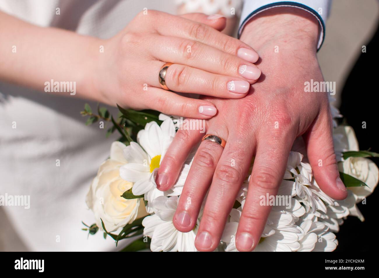 Ein strahlender Moment der Einheit: Die Liebe mit Hochzeitsringen und Blüten feiern. Stockfoto