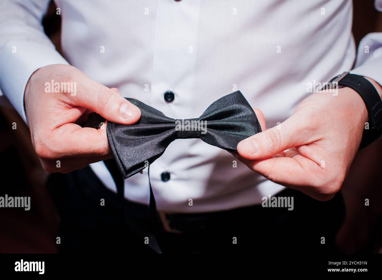 Elegant gekleideter Gentleman, der eine formelle schwarze Schleife vor einem Event anpasst. Stockfoto