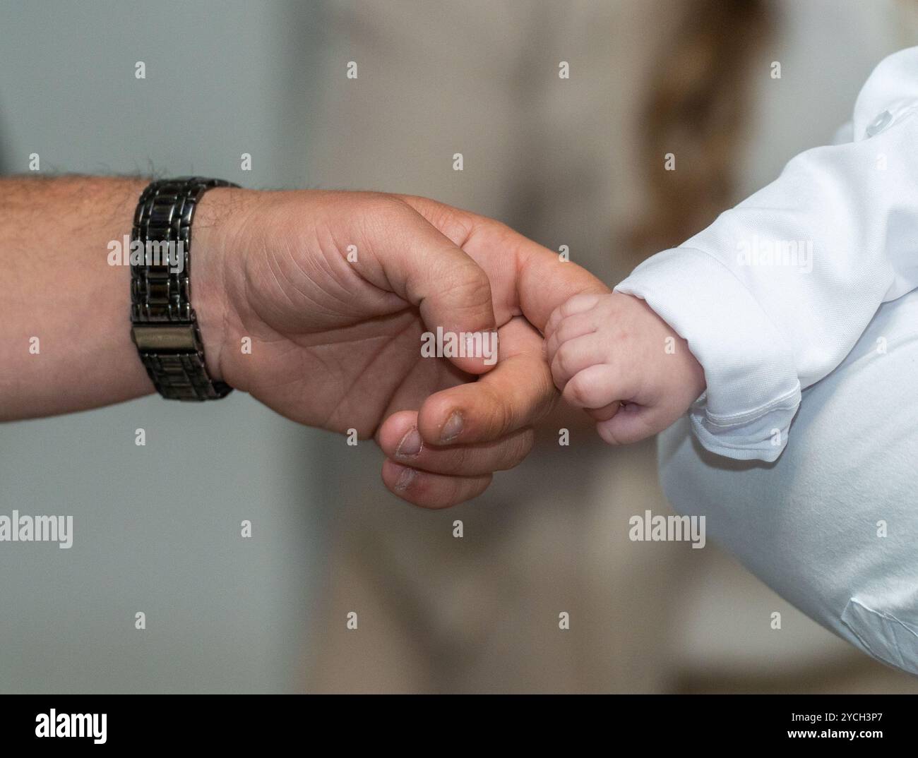 Vater und neugeborener Sohn am Tauftag: Ein sanfter Berührungsmoment. Stockfoto