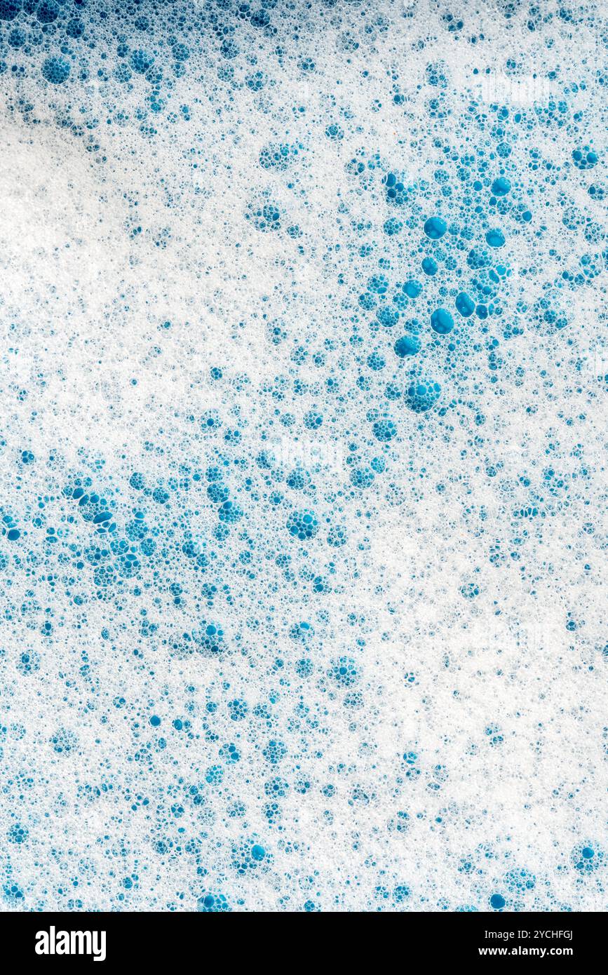 Hintergrund und Muster. Weißer Seifenschaum mit Blasen, Textur auf blauem Fliesenhintergrund. Reinigungsmittelschaumblase auf Fliesen. Duschgel, Haarshampoo Schaum sm Stockfoto