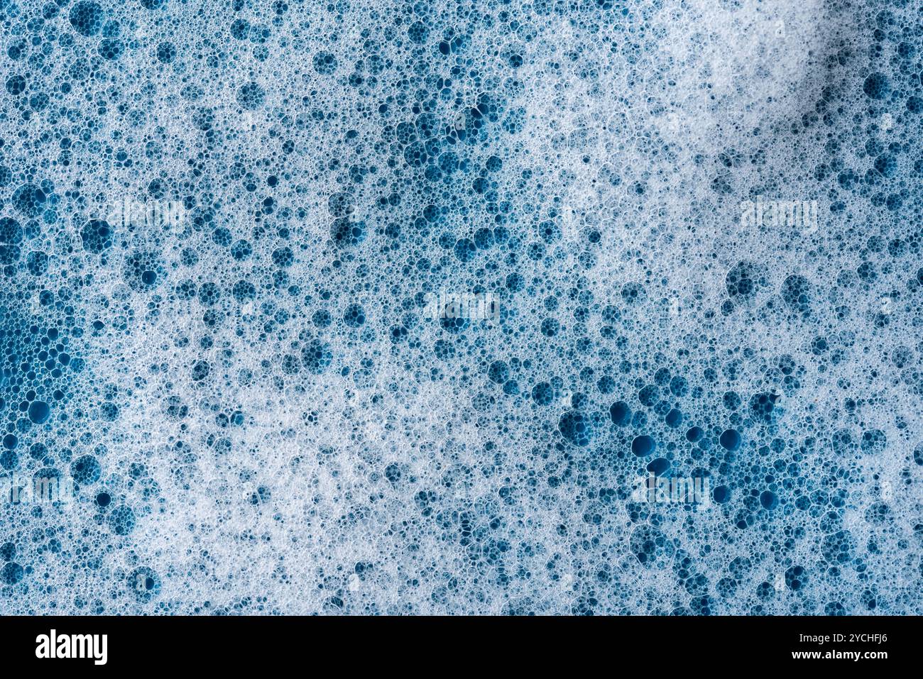 Hintergrund und Muster. Weißer Seifenschaum mit Blasen, Textur auf blauem Fliesenhintergrund. Reinigungsmittelschaumblase auf Fliesen. Duschgel, Haarshampoo Schaum sm Stockfoto