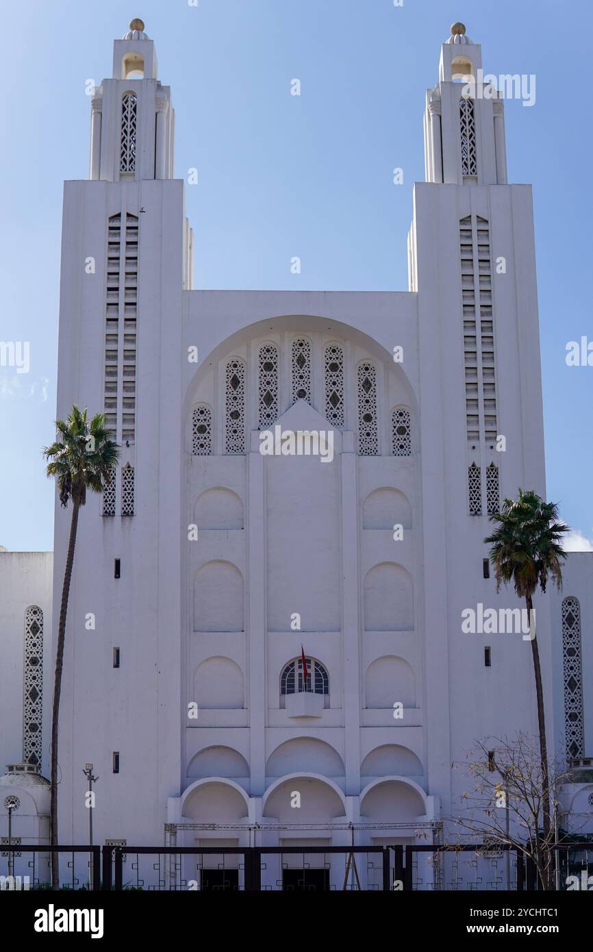die große, weiße Kathedrale mit zwei hohen Türmen und komplizierten Bögen, eine religiöse Struktur, wird von Palmen unter einem klaren blauen Himmel eingerahmt, der ausstrahlt Stockfoto