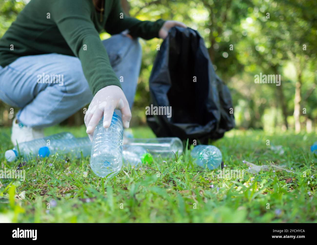 Frauen engagierter Freiwilliger nehmen an einer Umweltreinigungsaktion in einem Park Teil. Frau trägt Handschuhe und hält große schwarze Taschen. Frau Stockfoto