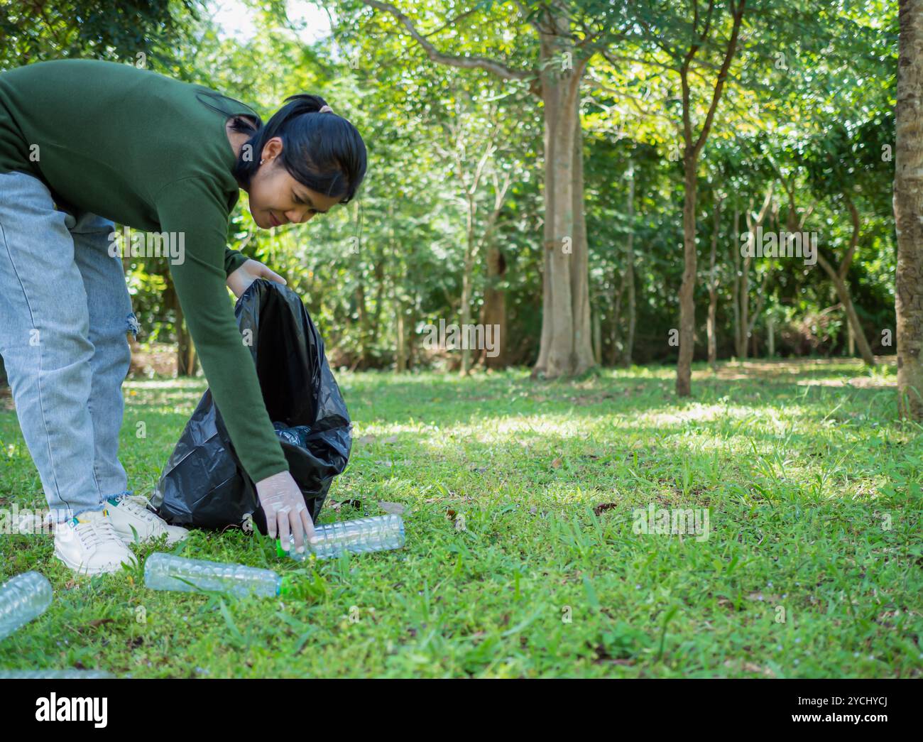 Frauen engagierter Freiwilliger nehmen an einer Umweltreinigungsaktion in einem Park Teil. Frau trägt Handschuhe und hält große schwarze Taschen. Frau Stockfoto