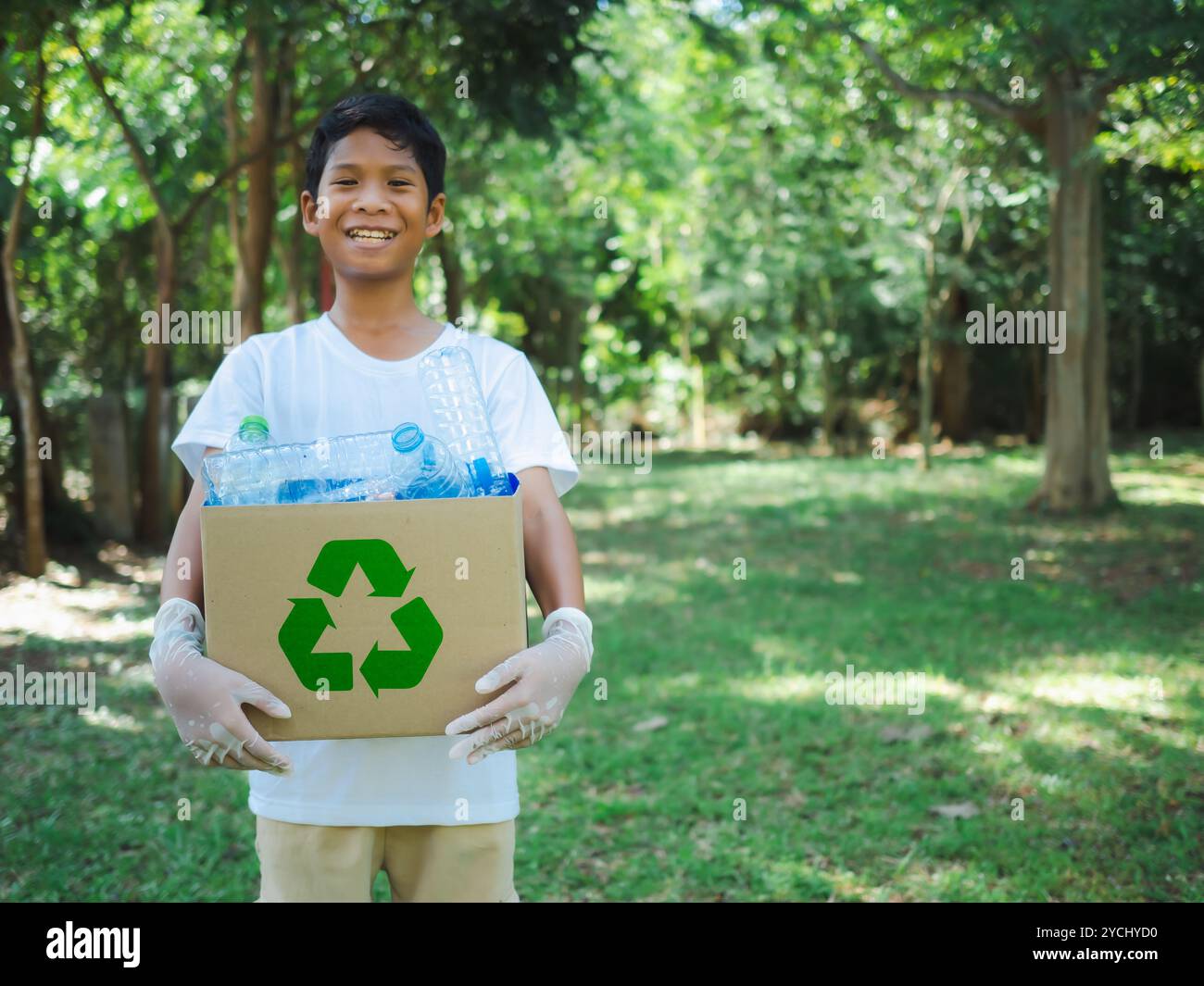 Boy hält Kartons zum Recycling und hält einen Papierkorb mit Plastikflaschen im Freien, um Umweltverschmutzung zu reduzieren und recyceln Stockfoto