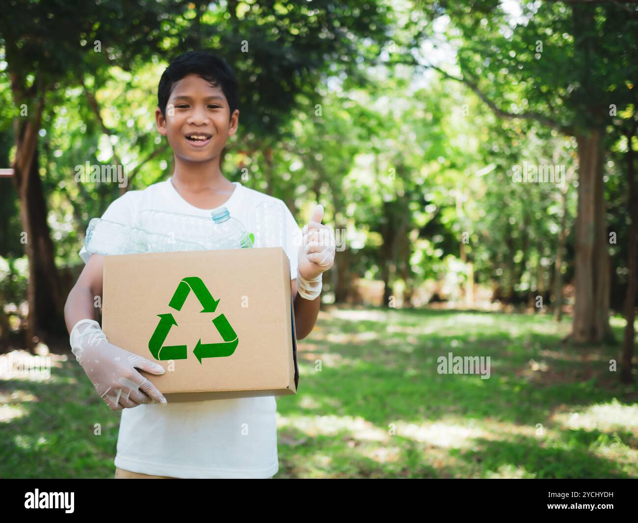 Boy hält Kartons zum Recycling und hält einen Papierkorb mit Plastikflaschen im Freien, um Umweltverschmutzung zu reduzieren und recyceln Stockfoto