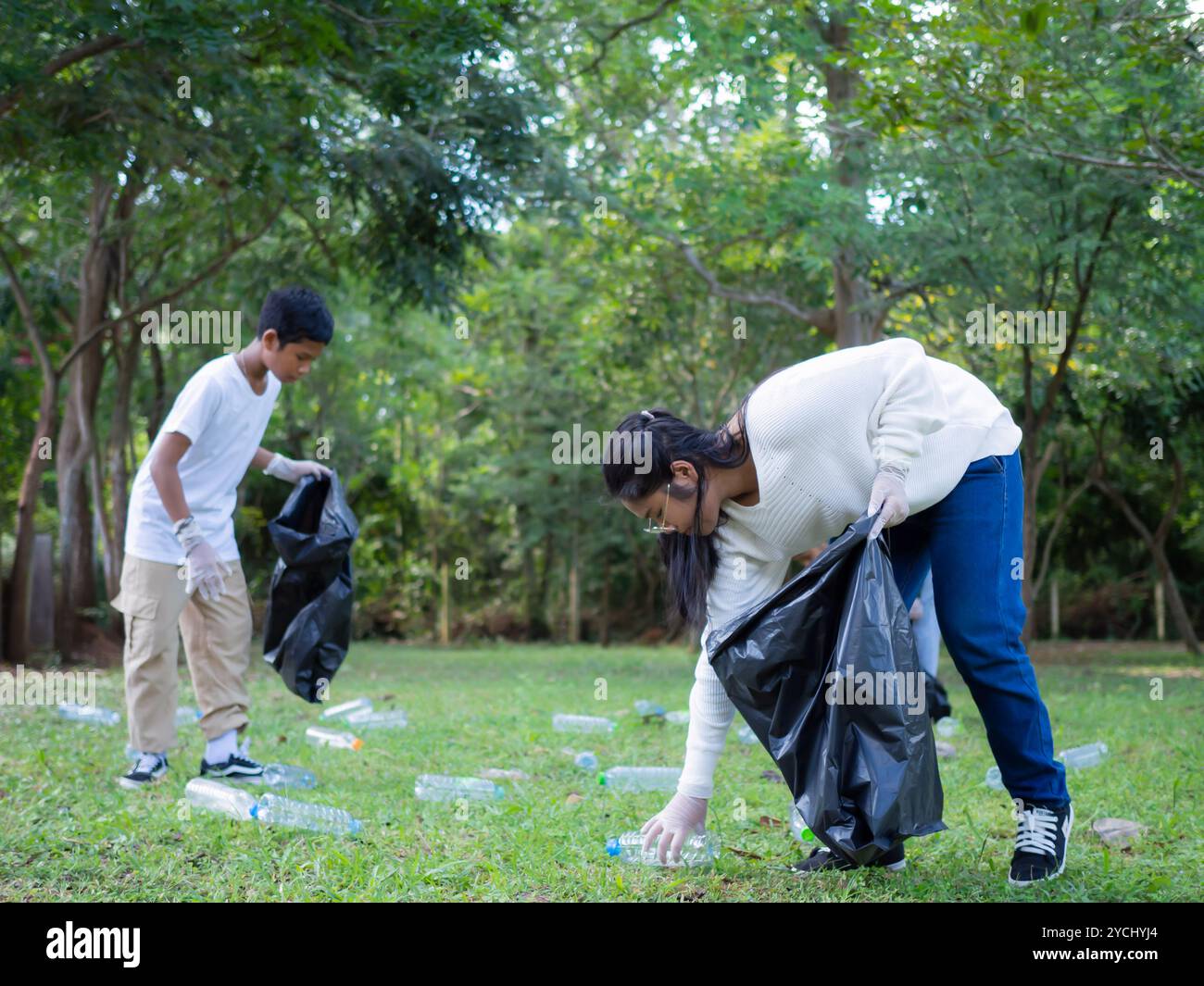 Eine Gruppe engagierter junger Freiwilliger nimmt an einer Umweltreinigung in einem Park Teil. Freiwillige halten große schwarze Taschen in der Hand. Personen A Stockfoto