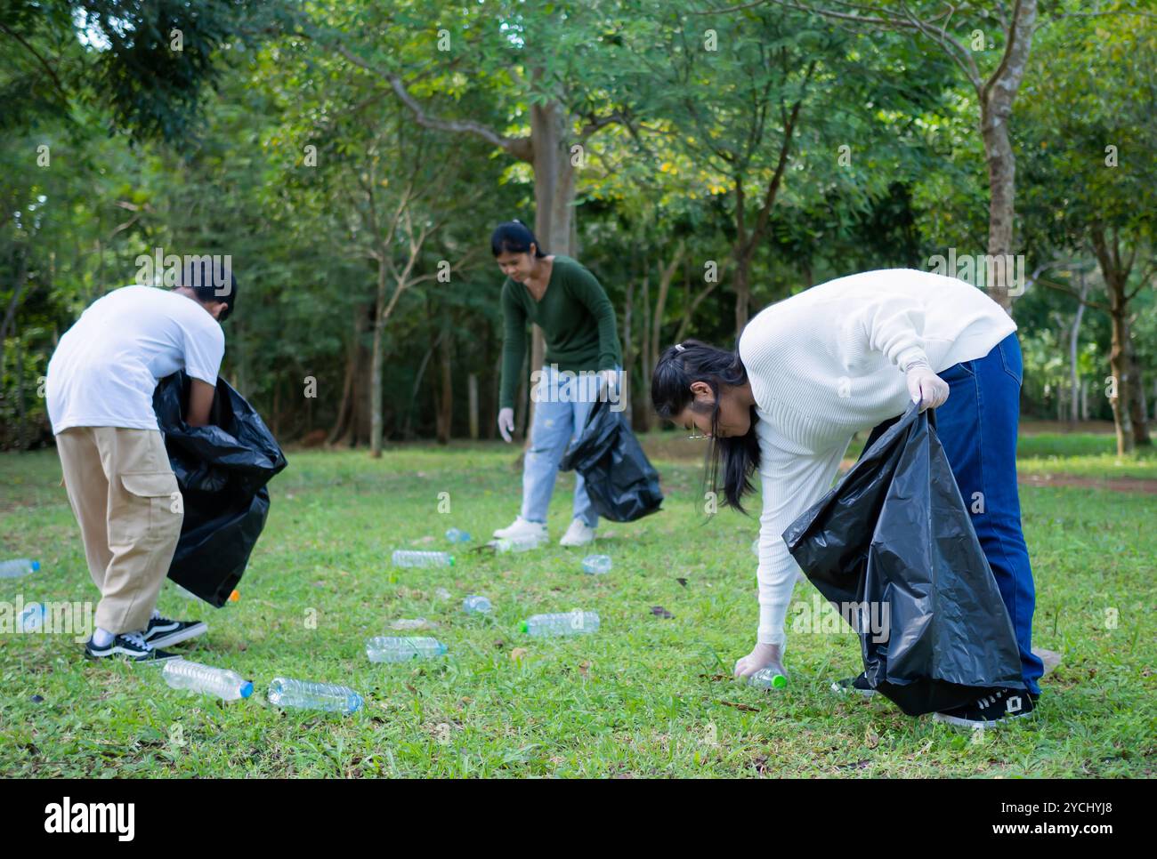 Eine Gruppe engagierter junger Freiwilliger nimmt an einer Umweltreinigung in einem Park Teil. Freiwillige halten große schwarze Taschen in der Hand. Personen A Stockfoto