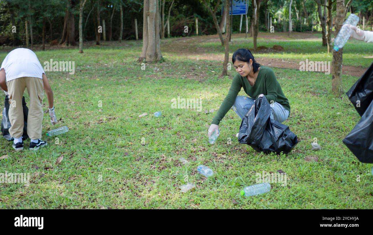 Eine Gruppe engagierter junger Freiwilliger nimmt an einer Umweltreinigung in einem Park Teil. Freiwillige halten große schwarze Taschen in der Hand. Personen A Stockfoto