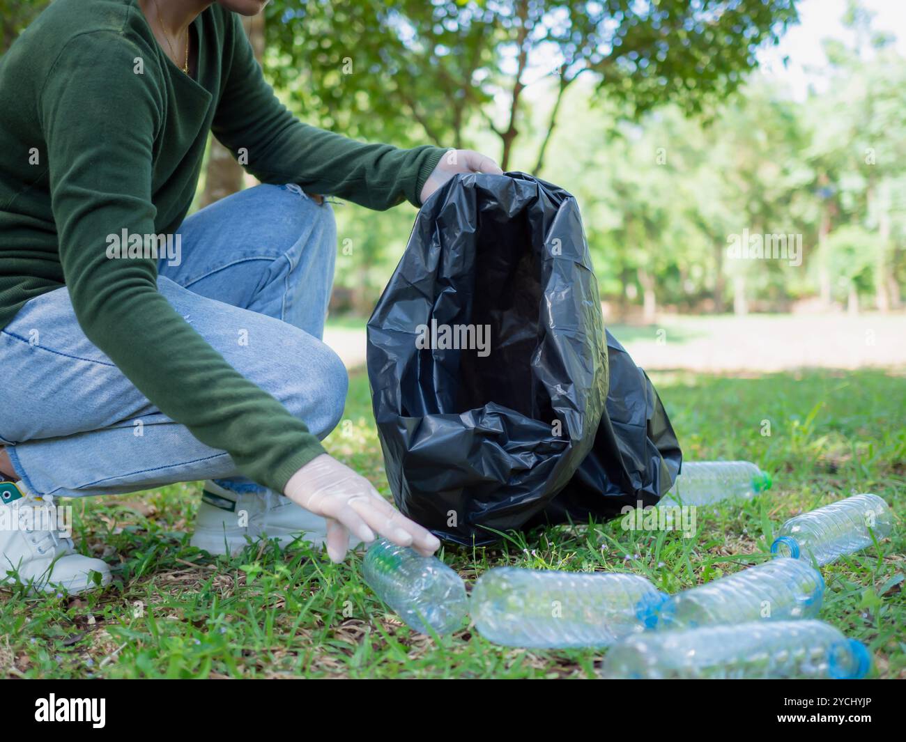 Frauen engagierter Freiwilliger nehmen an einer Umweltreinigungsaktion in einem Park Teil. Frau trägt Handschuhe und hält große schwarze Taschen. Frau Stockfoto