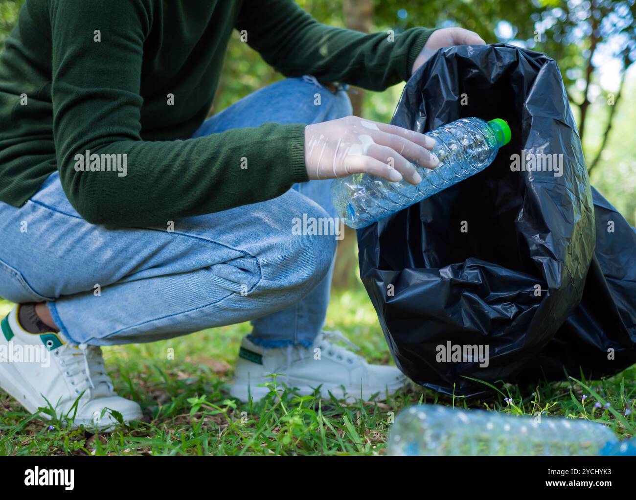 Frauen engagierter Freiwilliger nehmen an einer Umweltreinigungsaktion in einem Park Teil. Frau trägt Handschuhe und hält große schwarze Taschen. Frau Stockfoto