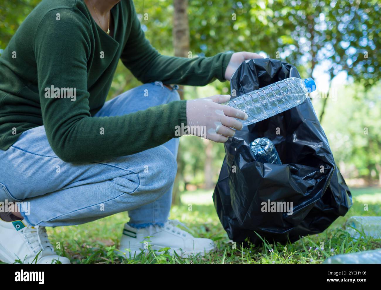 Frauen engagierter Freiwilliger nehmen an einer Umweltreinigungsaktion in einem Park Teil. Frau trägt Handschuhe und hält große schwarze Taschen. Frau Stockfoto