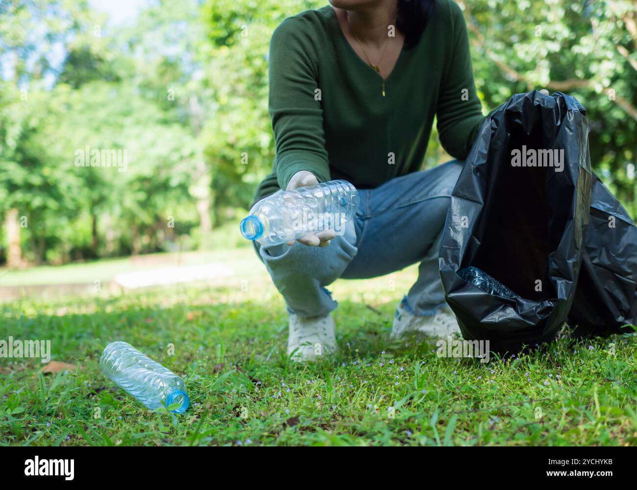 Frauen engagierter Freiwilliger nehmen an einer Umweltreinigungsaktion in einem Park Teil. Frau trägt Handschuhe und hält große schwarze Taschen. Frau Stockfoto