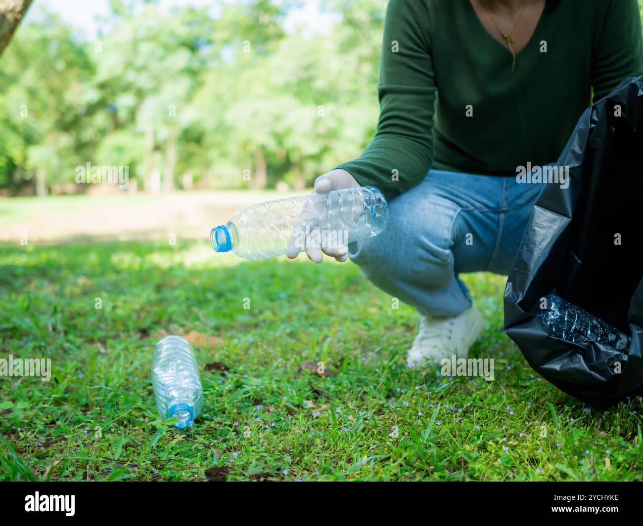 Frauen engagierter Freiwilliger nehmen an einer Umweltreinigungsaktion in einem Park Teil. Frau trägt Handschuhe und hält große schwarze Taschen. Frau Stockfoto