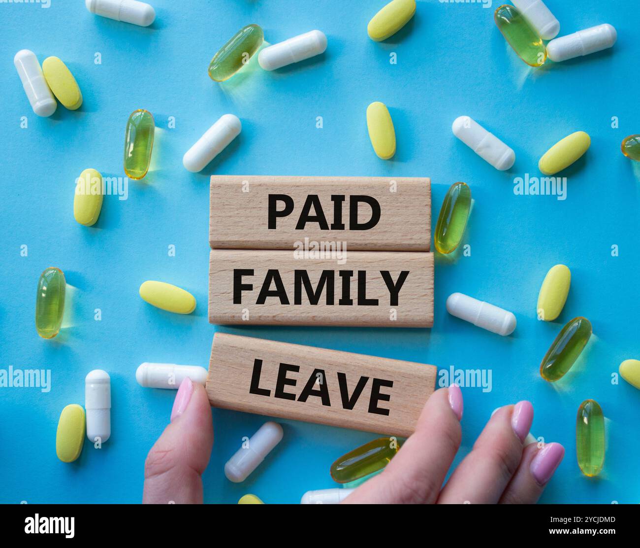 Symbol für bezahlten Familienurlaub. Concept Words bezahlte Familienurlaube auf Holzblöcken. Schöner blauer Hintergrund mit Pillen. Arzthand. Gesundheitswesen und bezahlte Fam Stockfoto