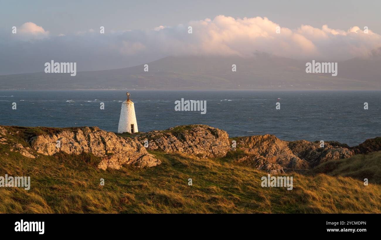 TWR Bach leuchtet im letzten Licht der goldenen Stunde auf Llanddwyn Island und überblickt die Menai-Straße mit dem Ufer von Eryri dahinter. Stockfoto